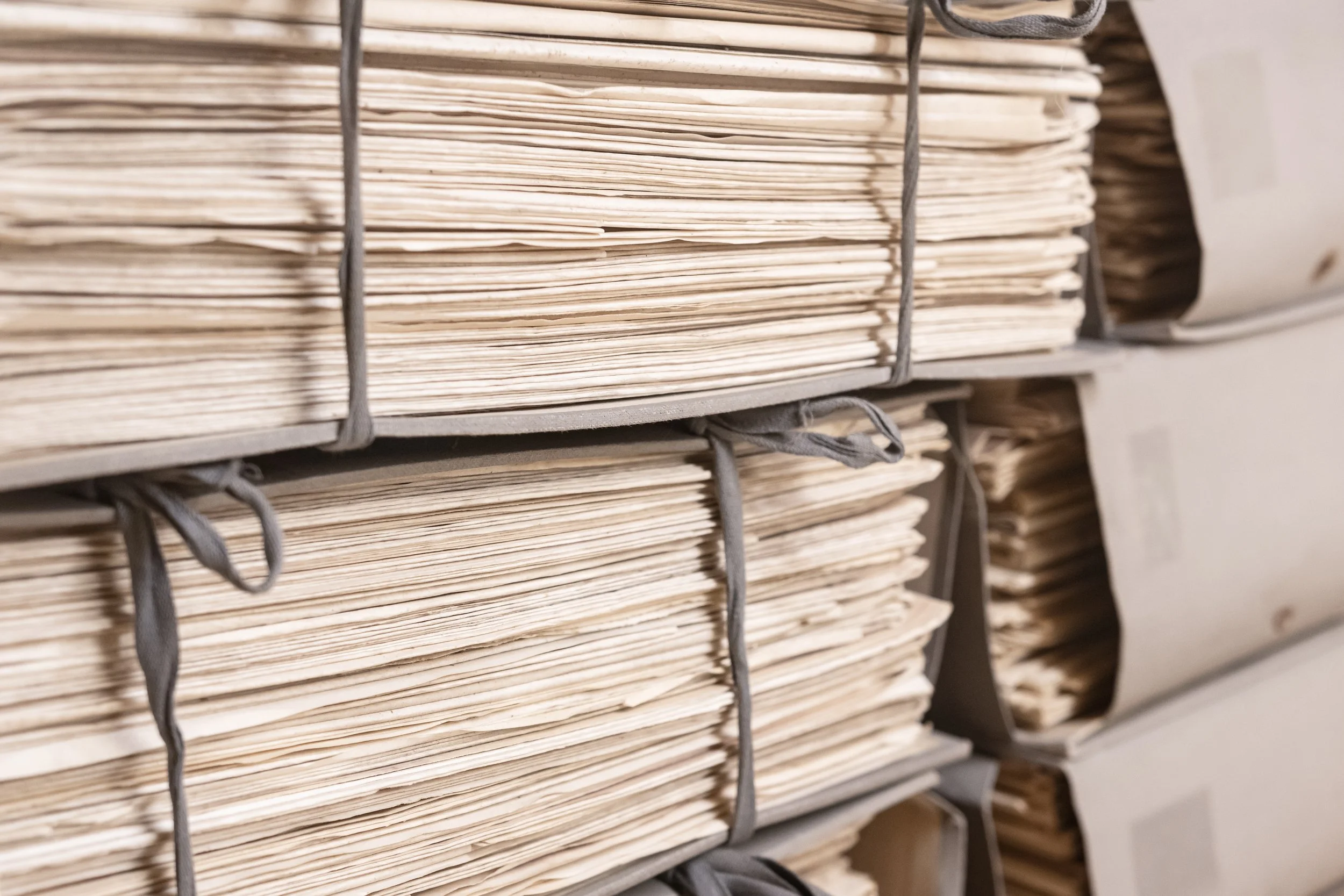 Stacks of paper files in a gray metal file organizer.