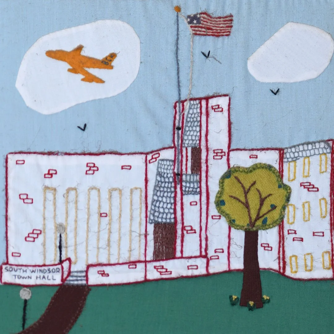 Embroidery artwork of South Windsor Town Hall with a tree and American flag in the sky.