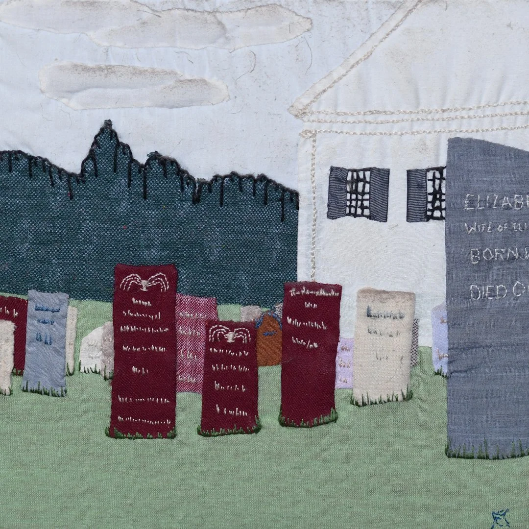 Embroidery art depicting a graveyard with tombstones, mountains, and a cloudy sky background.