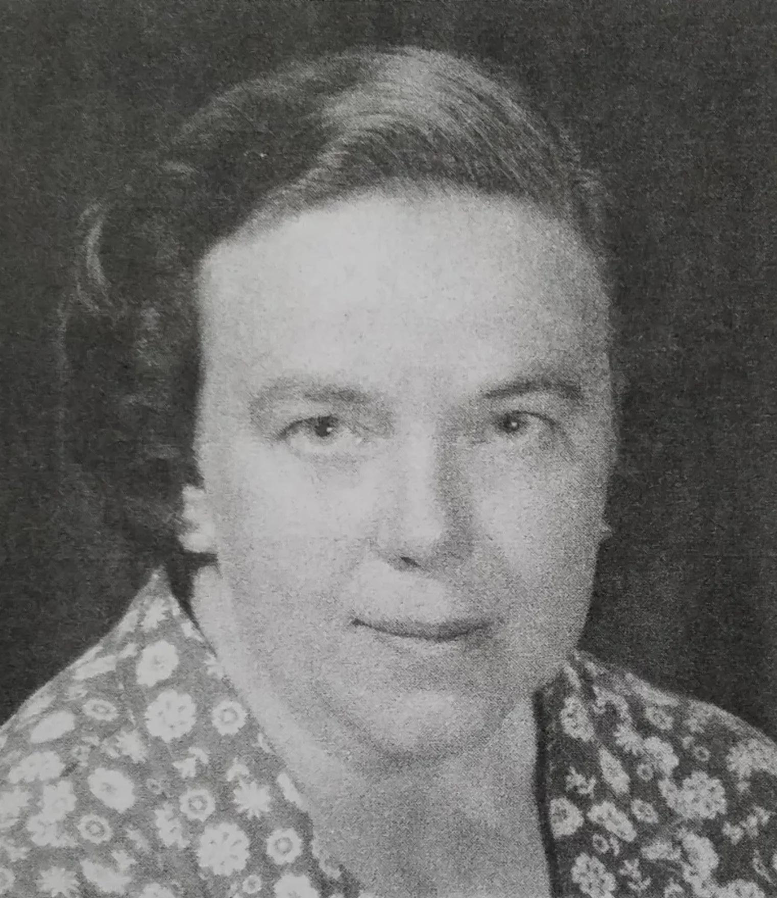 A black and white photo of a woman with short, styled hair, wearing traditional Asian clothing with floral patterns.