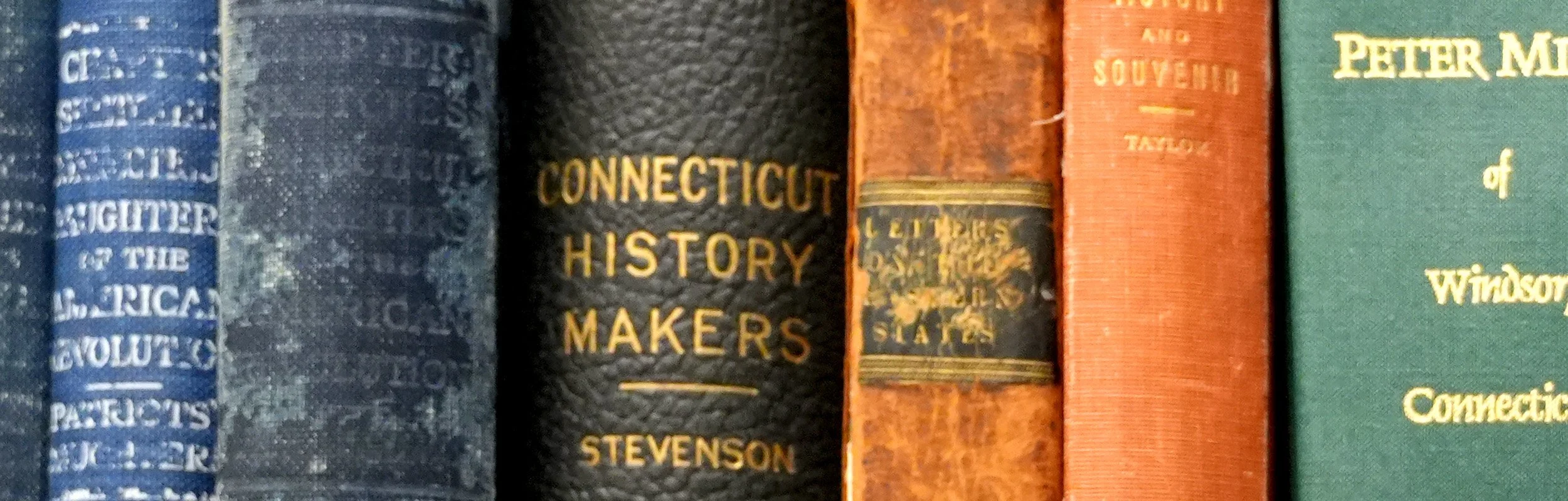 Row of old, worn books on a shelf, including titles about American history and Connecticut history.