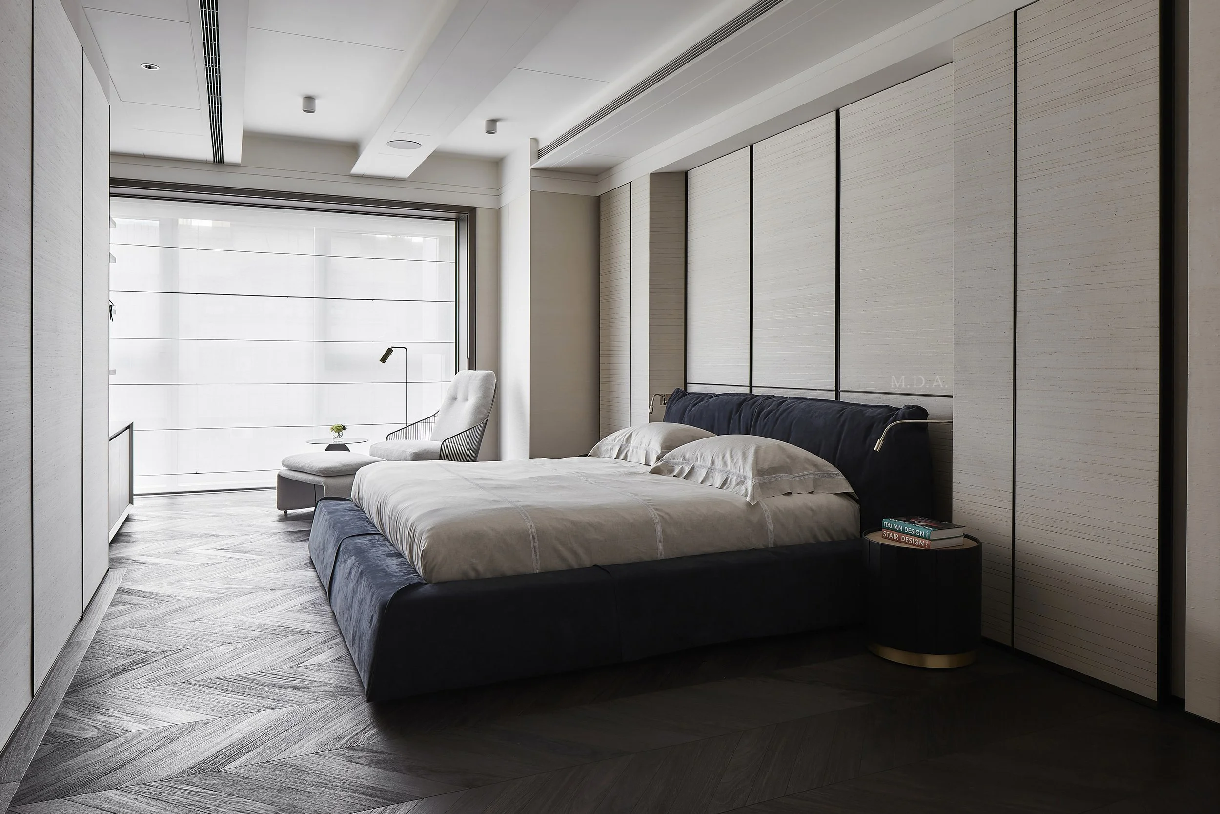 Modern bedroom with a large bed, a chair near the window, and minimal decor.