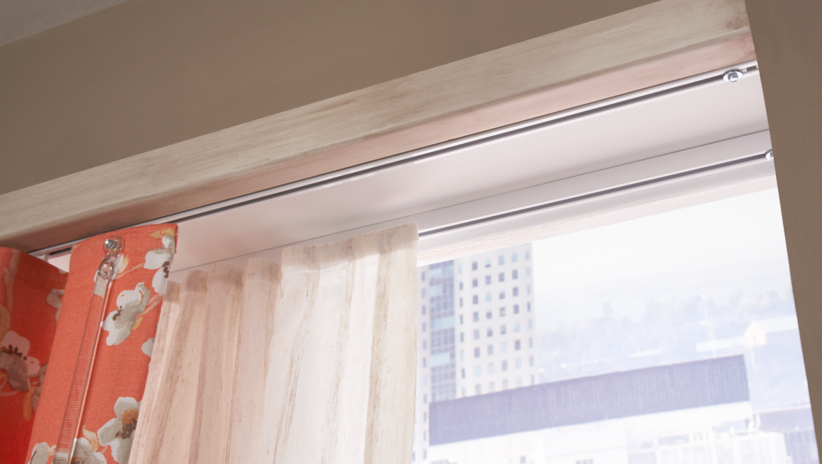 Partially opened window with beige and floral curtains in a high-rise building, cityscape visible outside.
