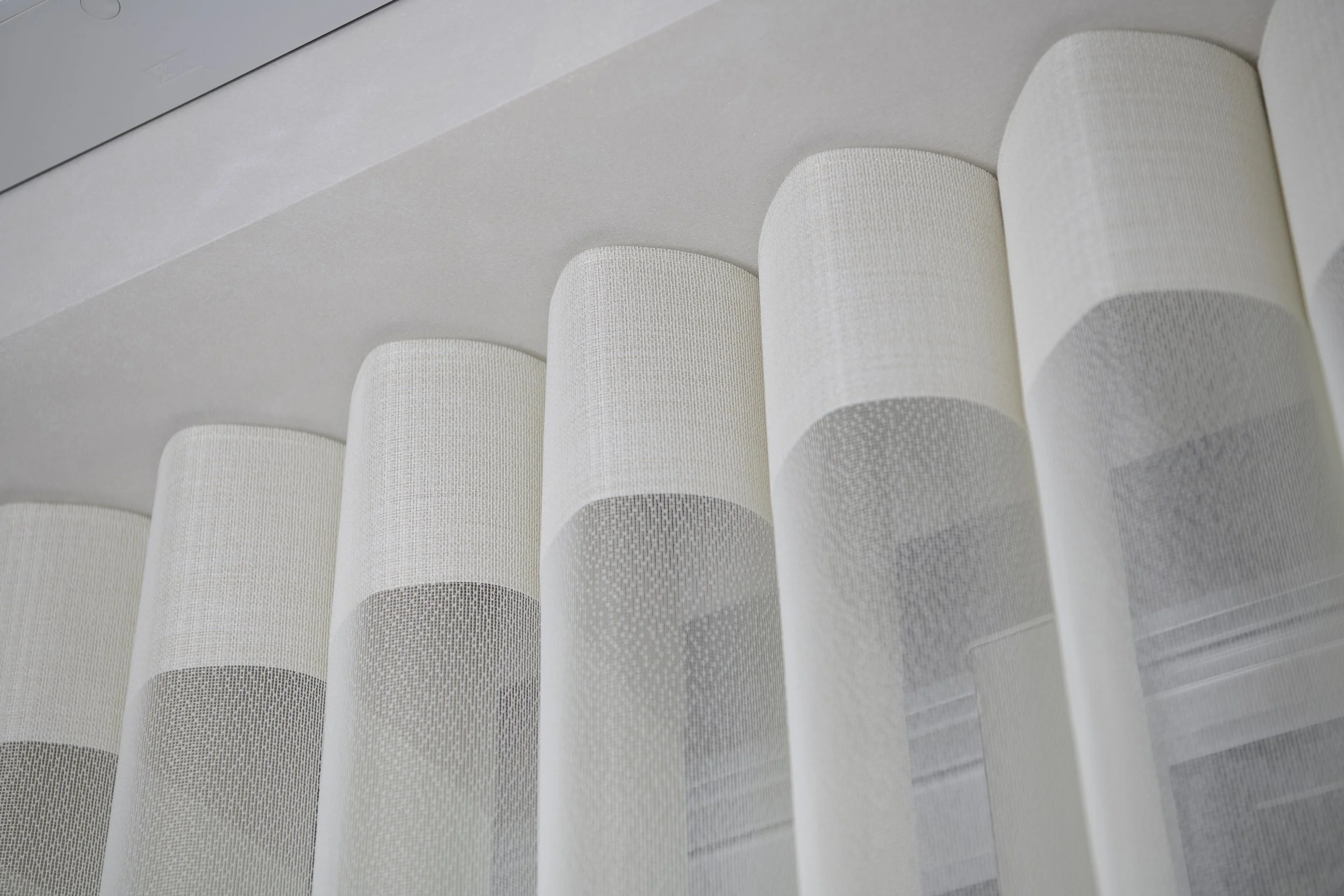 Close-up of white, textured window blinds partially covering a window in a modern interior.