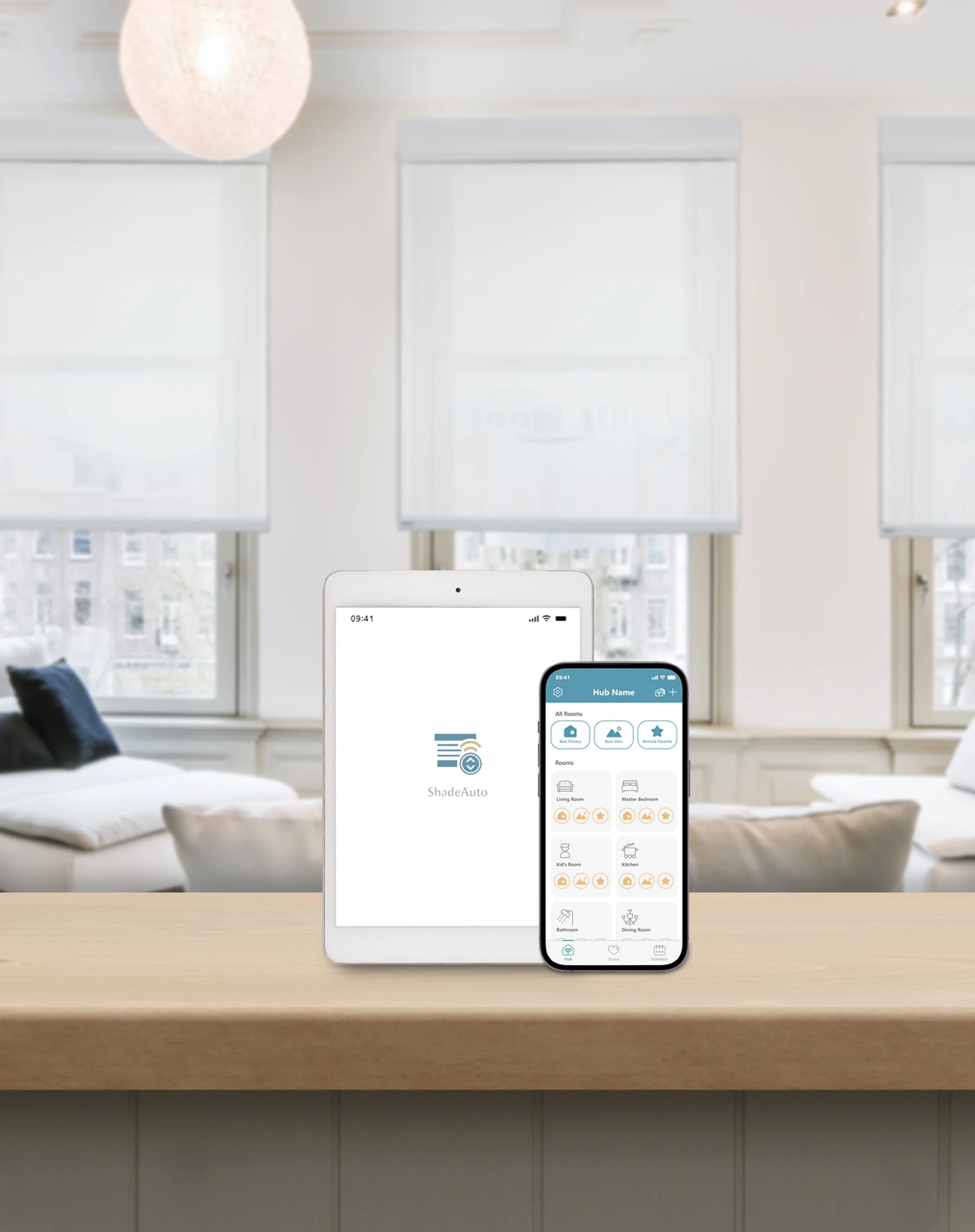 Smartphone and tablet displaying the ShadeAuto app on a wooden kitchen counter, with a white living room with large windows and white blinds in the background.