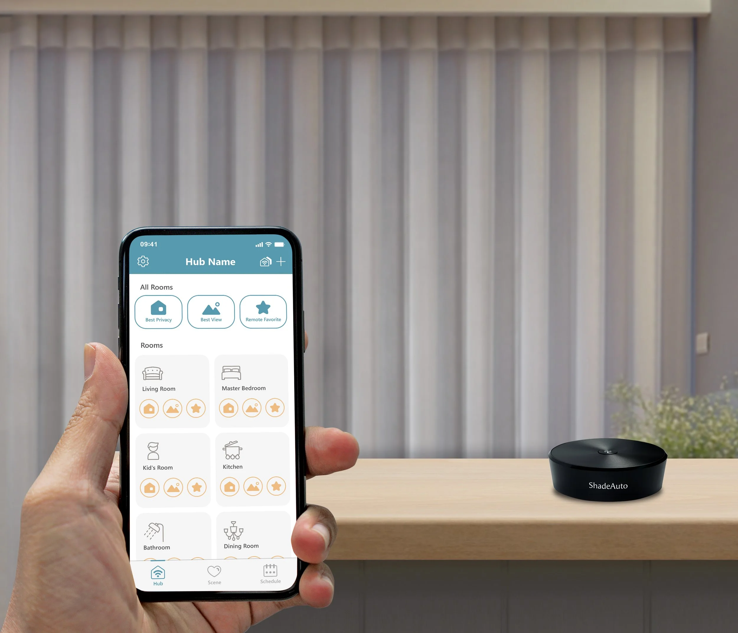 A person holding a smartphone displaying a smart home app, with a black ShadeAuto device on a wooden surface and a gray vertical panel wall in the background.