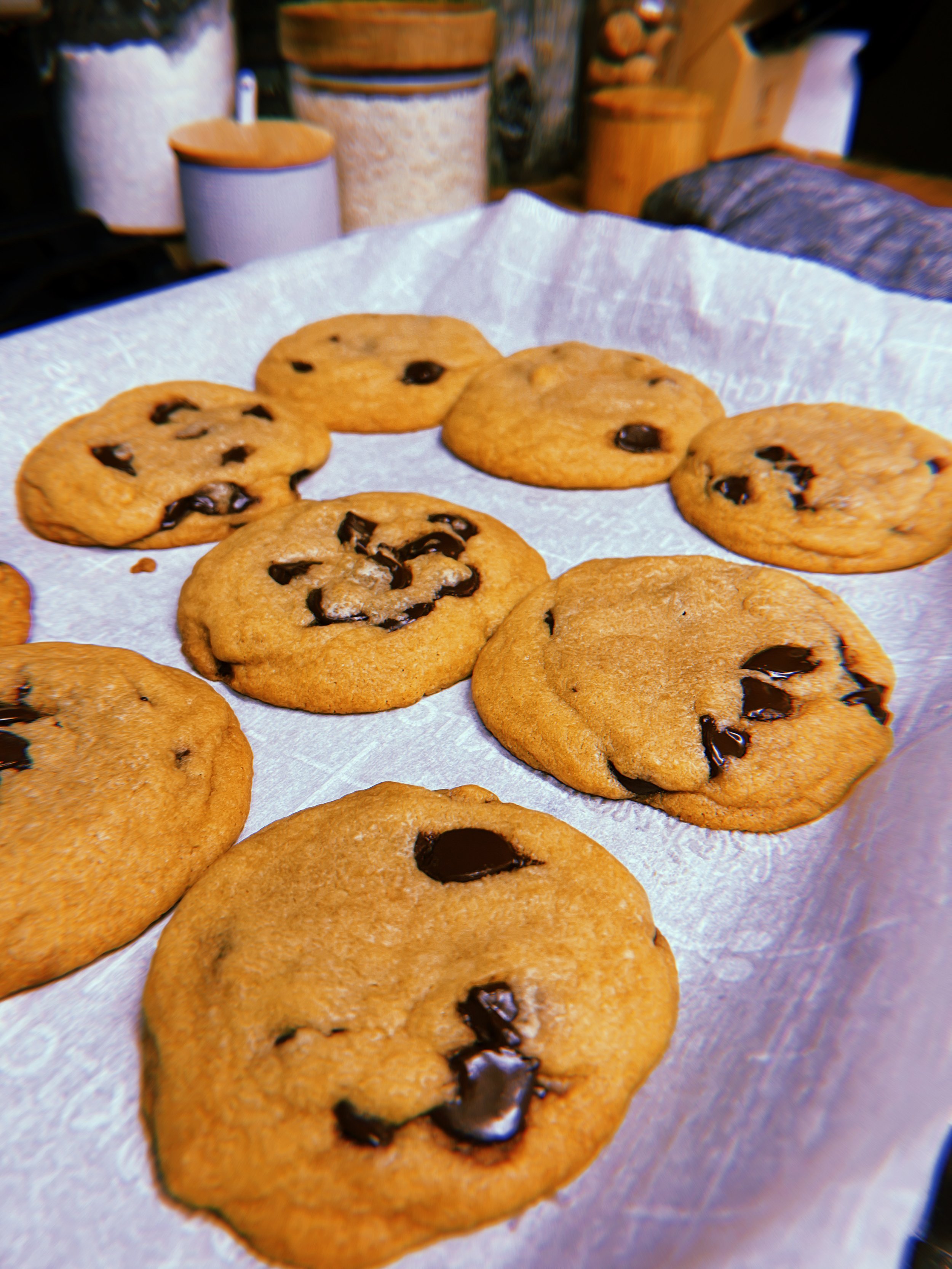 Several chocolate chip cookies on a parchment paper-lined tray.