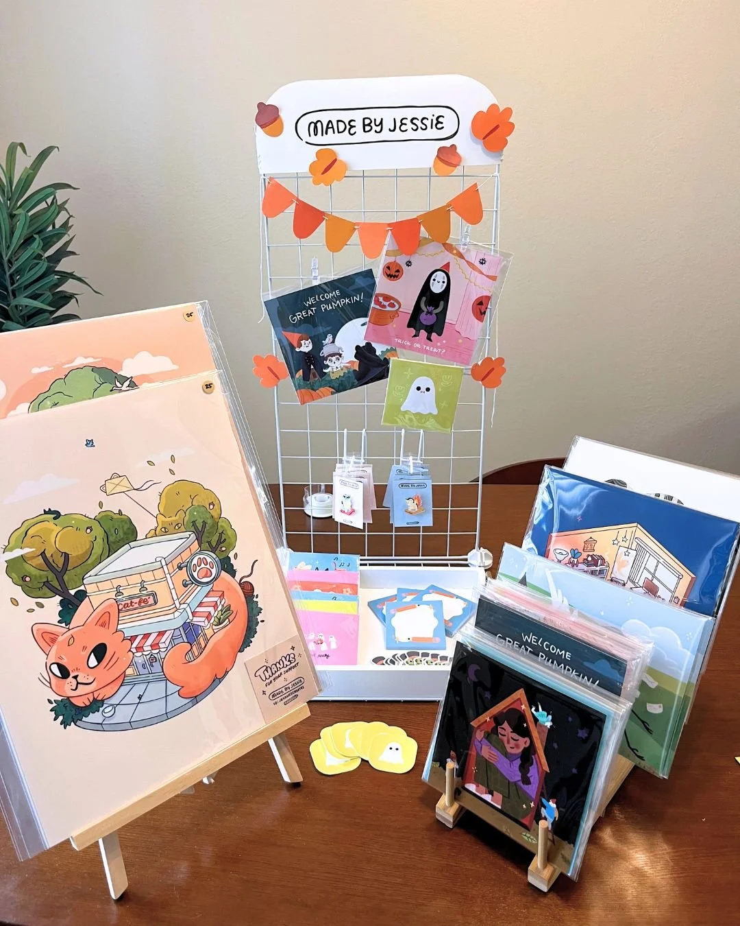 Display of Halloween-themed greeting cards, artwork, and decorations on a table.