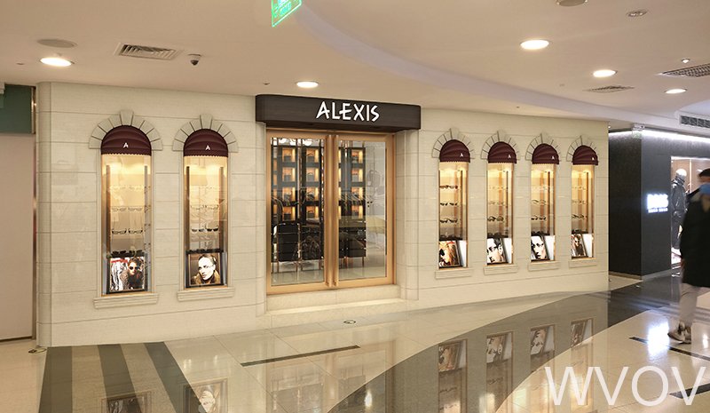 Storefront of Alexis beauty salon with five display windows and a glass door entrance, in a mall corridor.