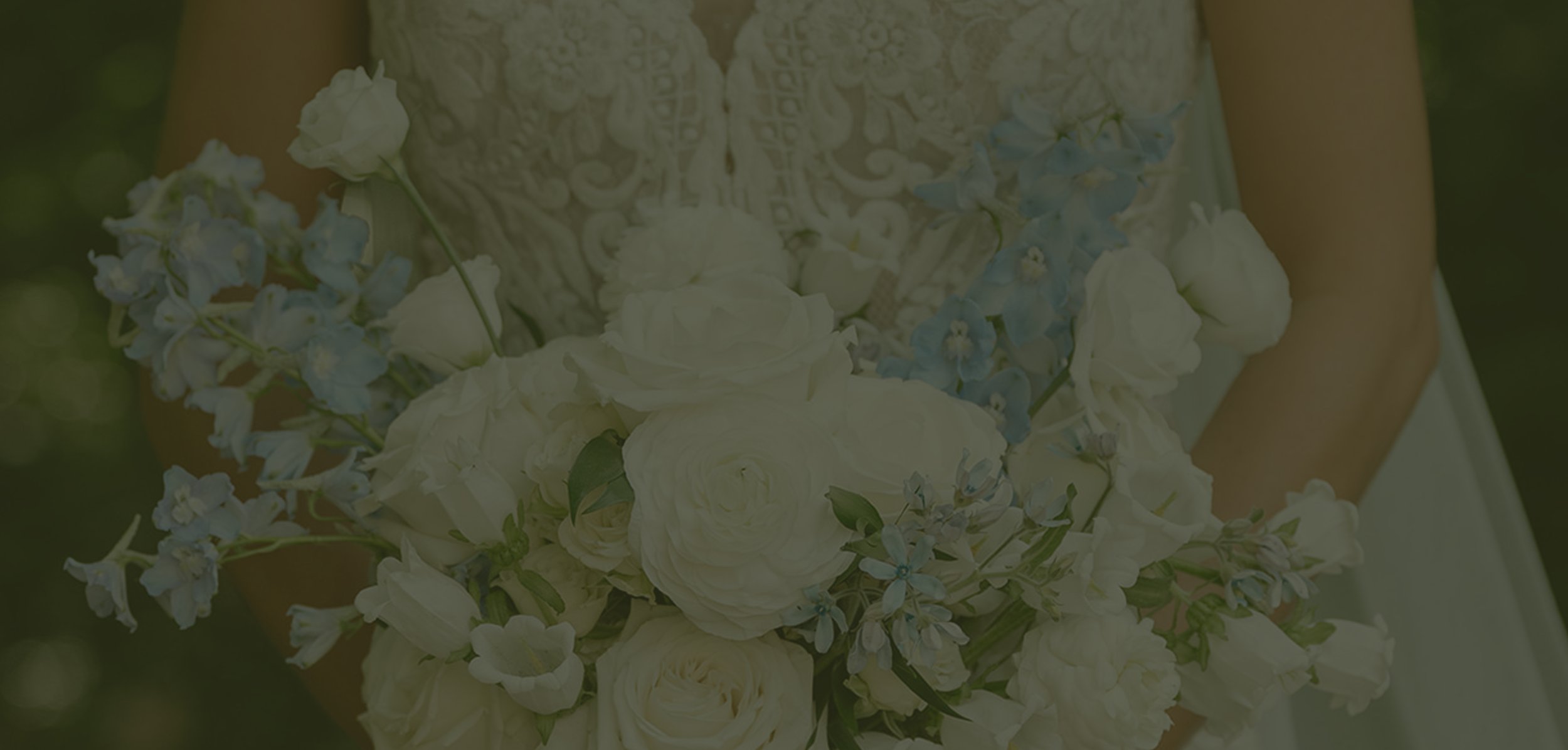 A wedding bride holding a bouquet of white and light blue flowers, with a lace wedding dress visible.