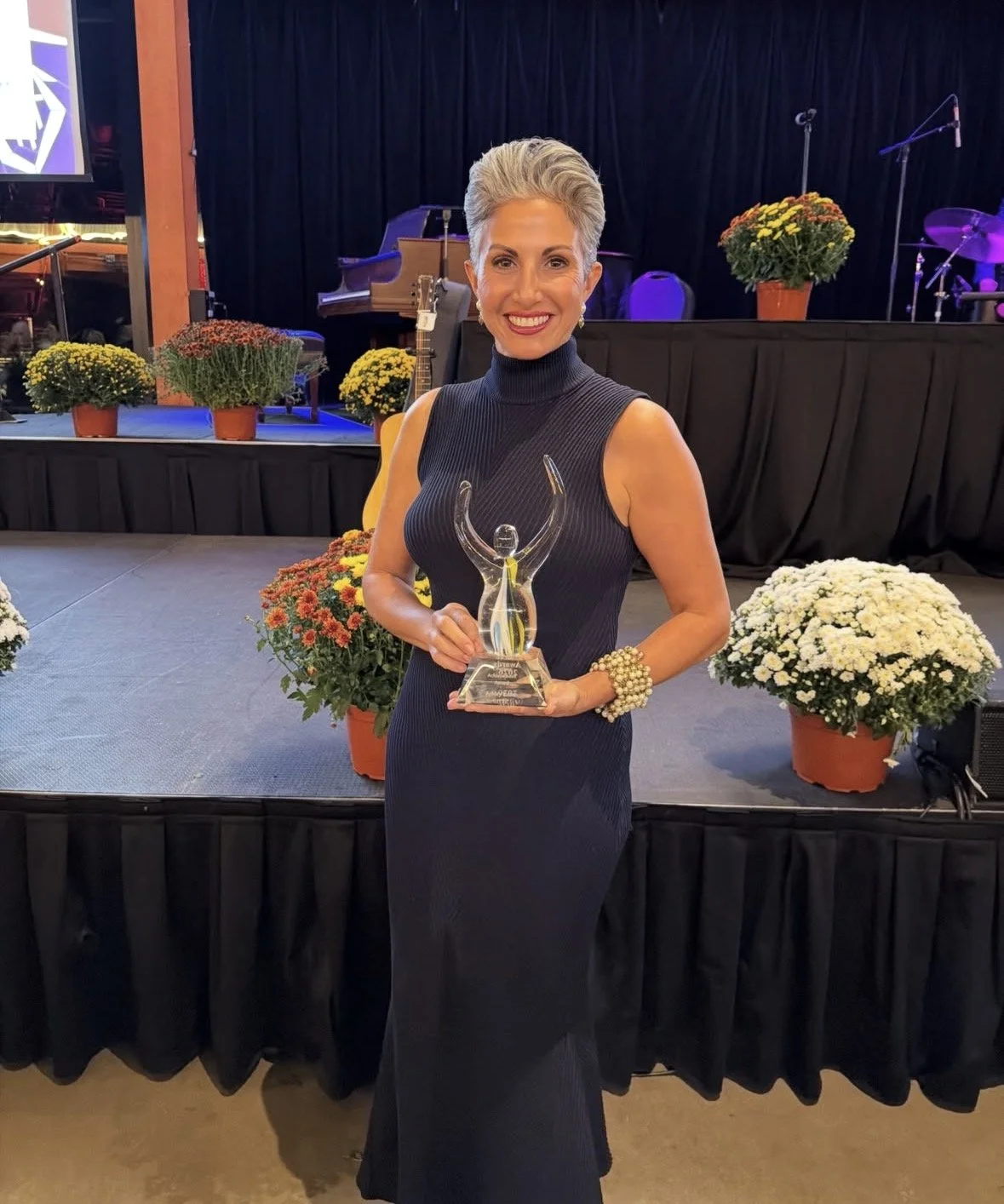 Ashley Russo smiling with her award while wearing a blue dress