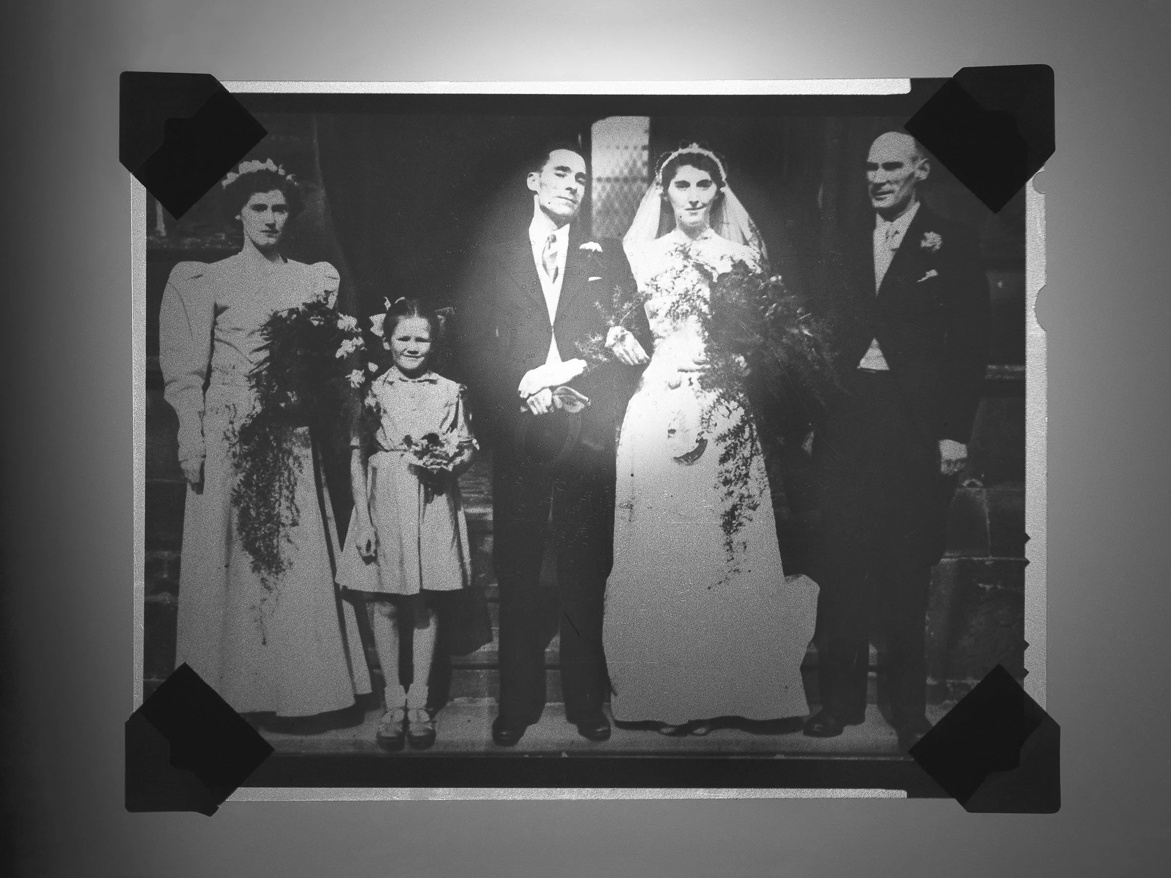 Black and white vintage wedding photograph showing a bride and groom with two young girls and two women standing beside them.