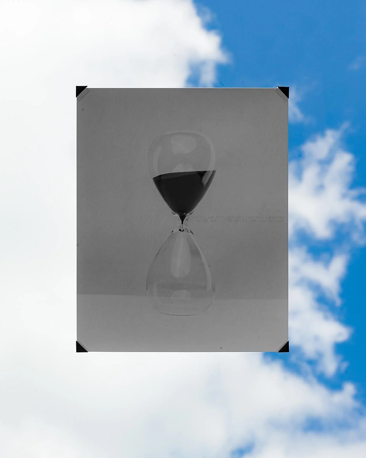 A billboard displaying an upside-down hourglass with black sand against a partly cloudy sky.