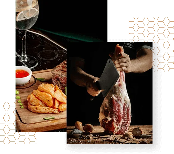 A person preparing a large cut of raw beef with a meat cleaver at a wooden table, with scattered garlic cloves and mushrooms; left side shows a glass of wine, a plate of potato wedges, and a sauce bowl, against a dark background.