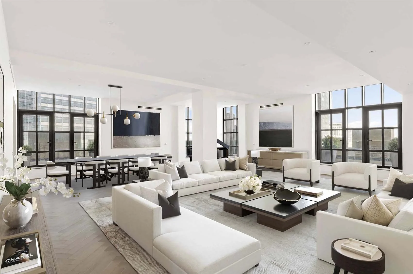 Modern, spacious living room with white sofas, black and white decor, large black-framed windows, and a minimalist design.