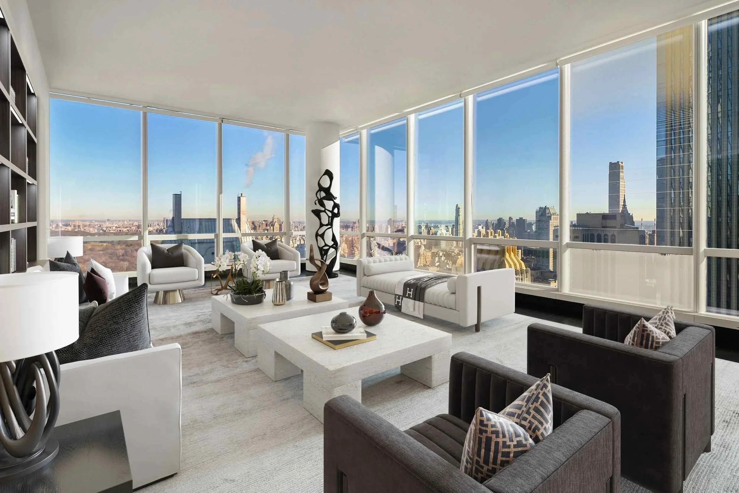 Modern living room with large windows showcasing a city skyline. The room has white and black furniture, decorative art pieces, and a neutral-toned rug.