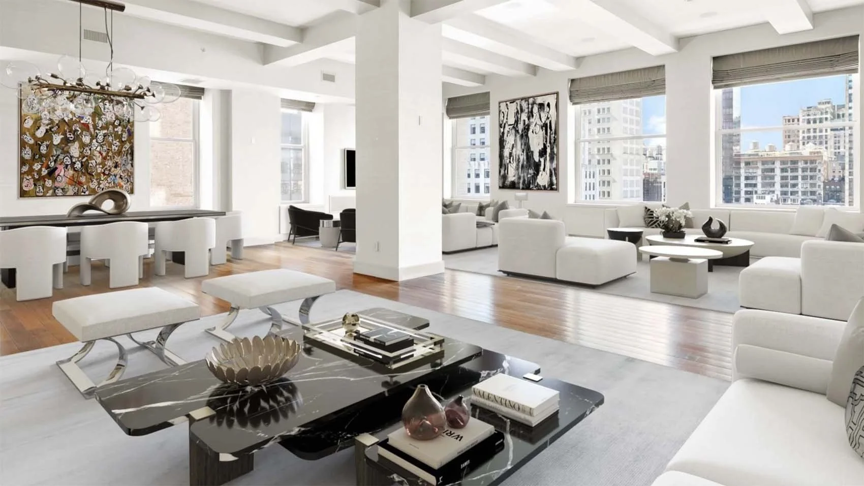 Modern bright living room with white furniture, art on the walls, large windows showing city buildings, and wooden flooring.