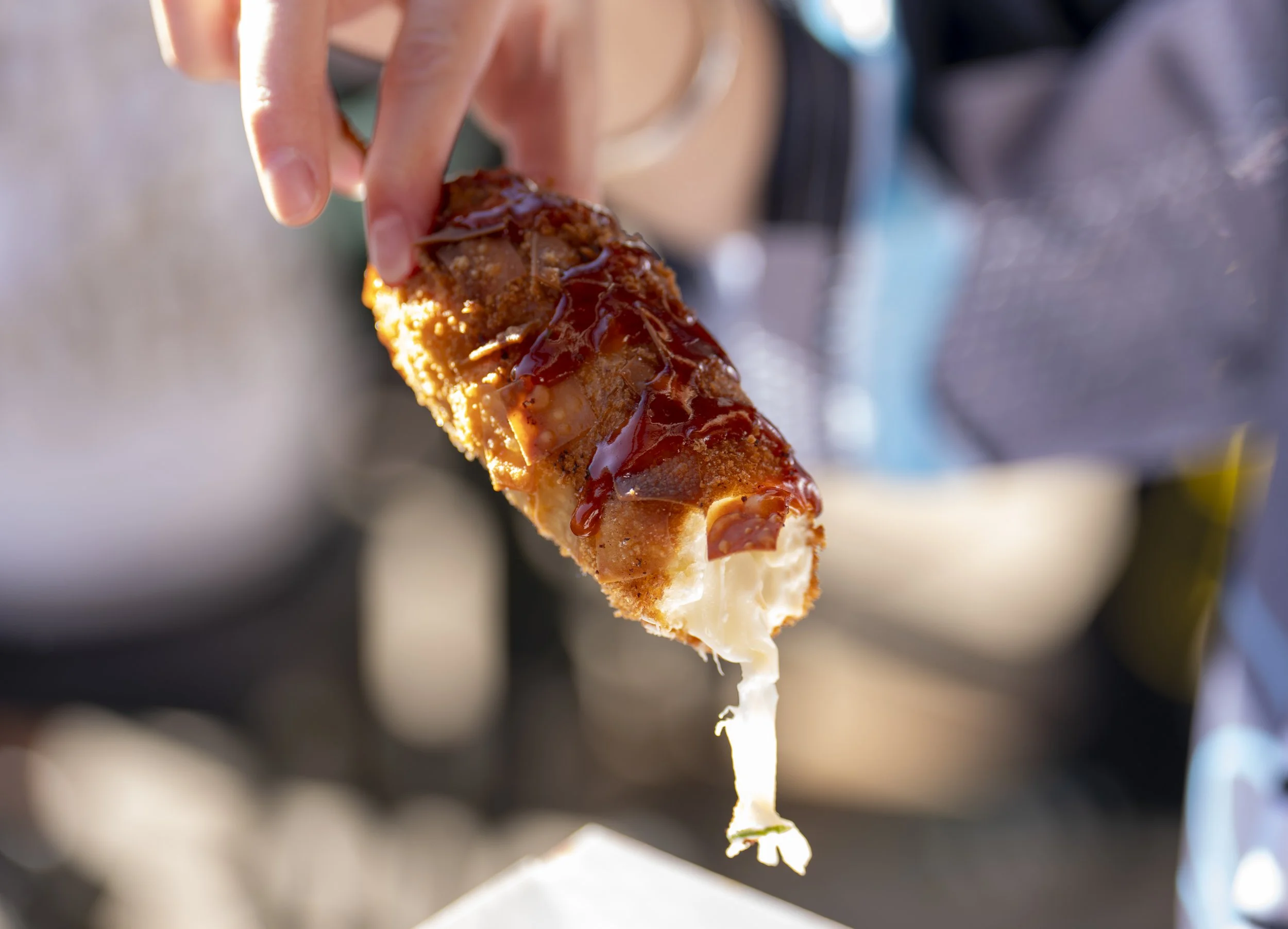 A modern wooden house on a grassy hillside with a lake and mountains in the background at sunset.