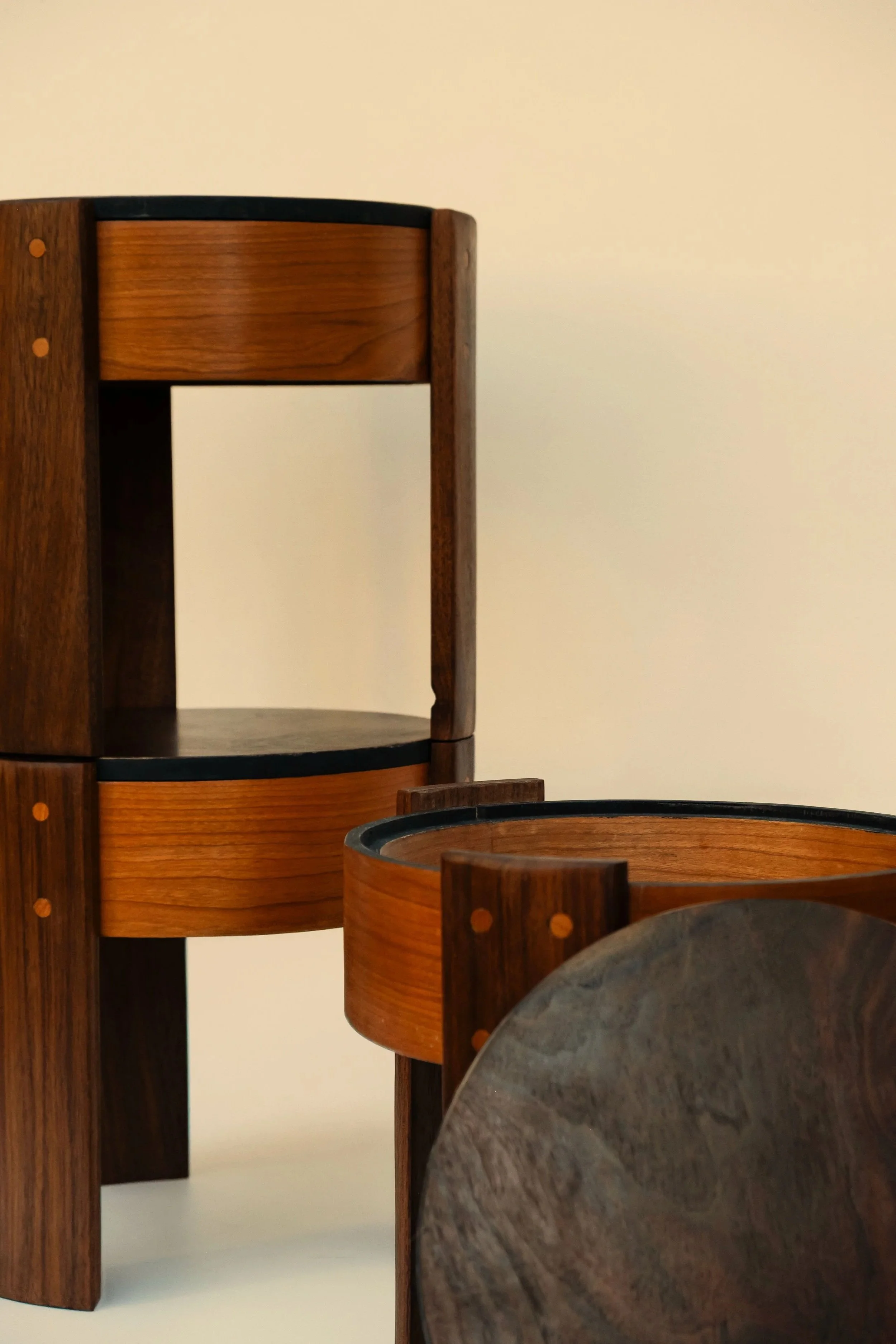 Close-up of two modern wooden stools stacked with circular forms and a combination of dark and light wood finishes.