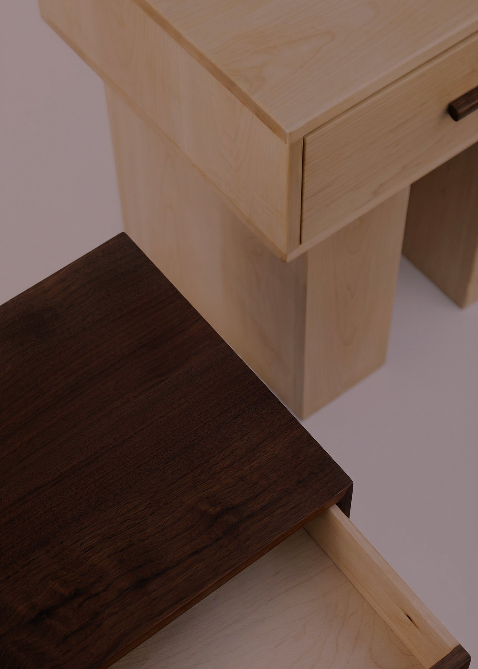Close-up of overlapping wooden furniture pieces, including a light-colored wood and a darker wood table.