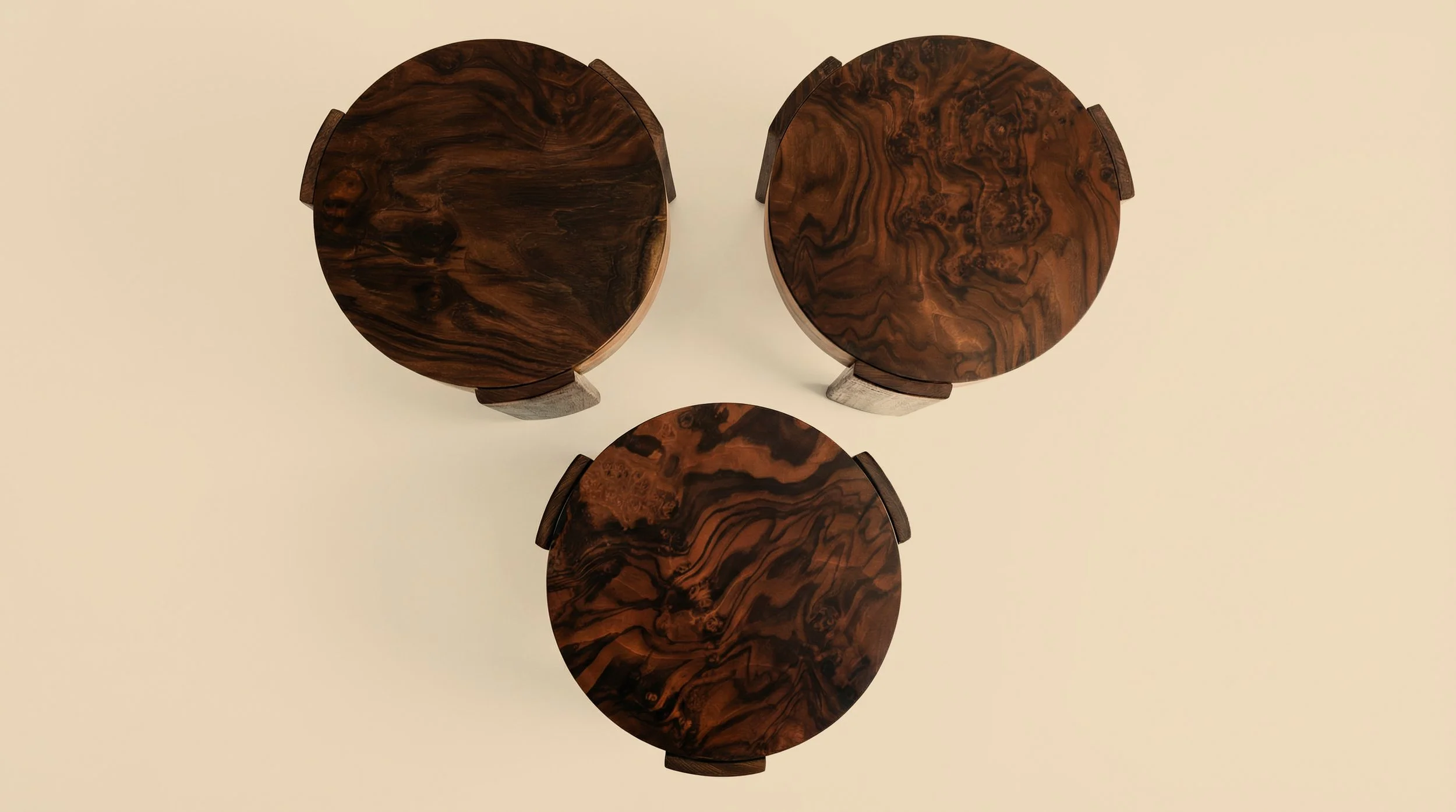 Three round wooden tables with dark, intricate wood grain patterns arranged in a triangle on a white background.