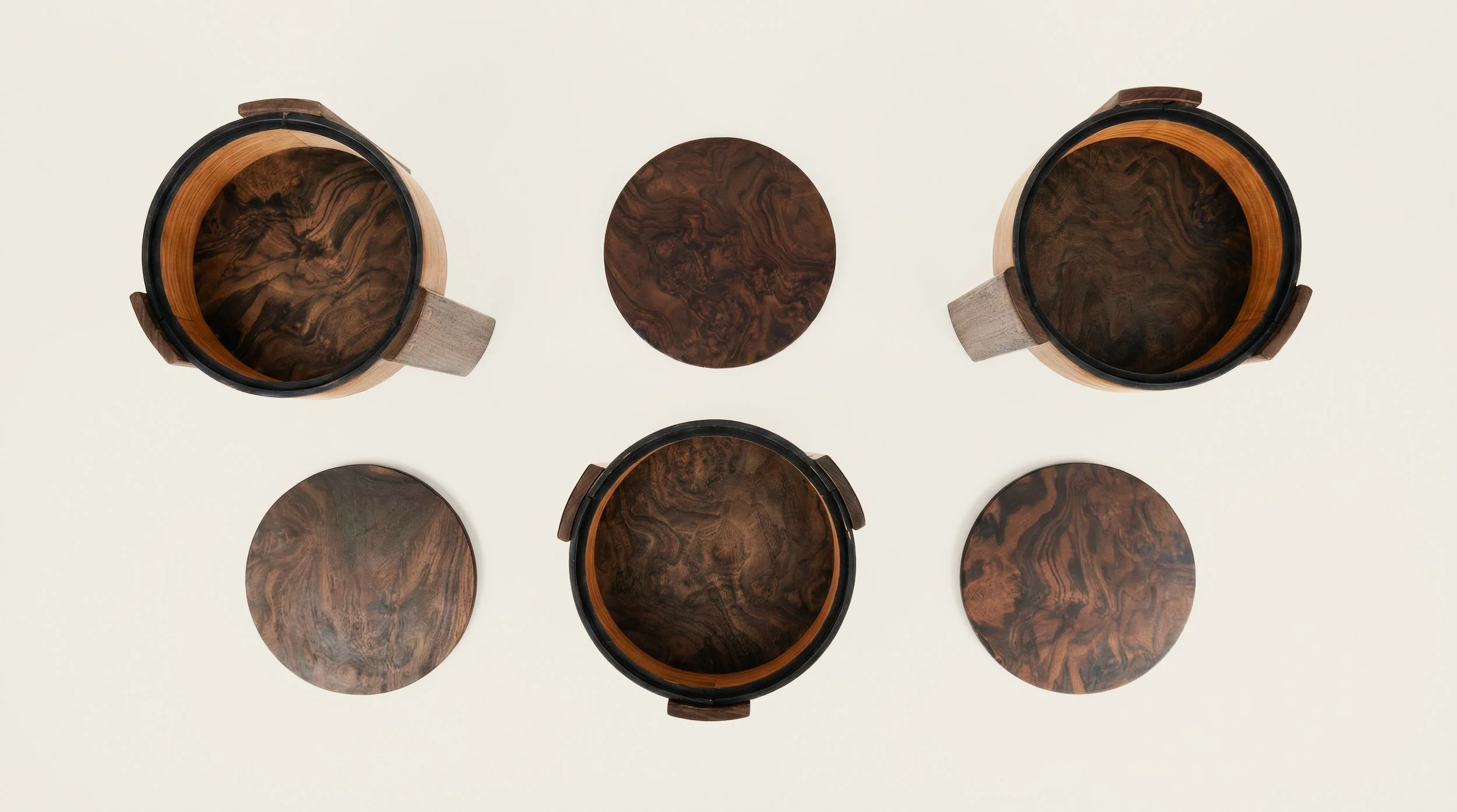 Bird's-eye view of three wooden stools with dark inner surfaces and three round wooden removable lids on a white background.