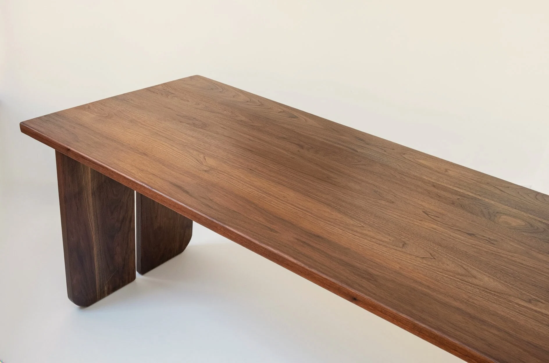 A wooden table with a smooth finish and rounded legs, set against a plain light-colored background.