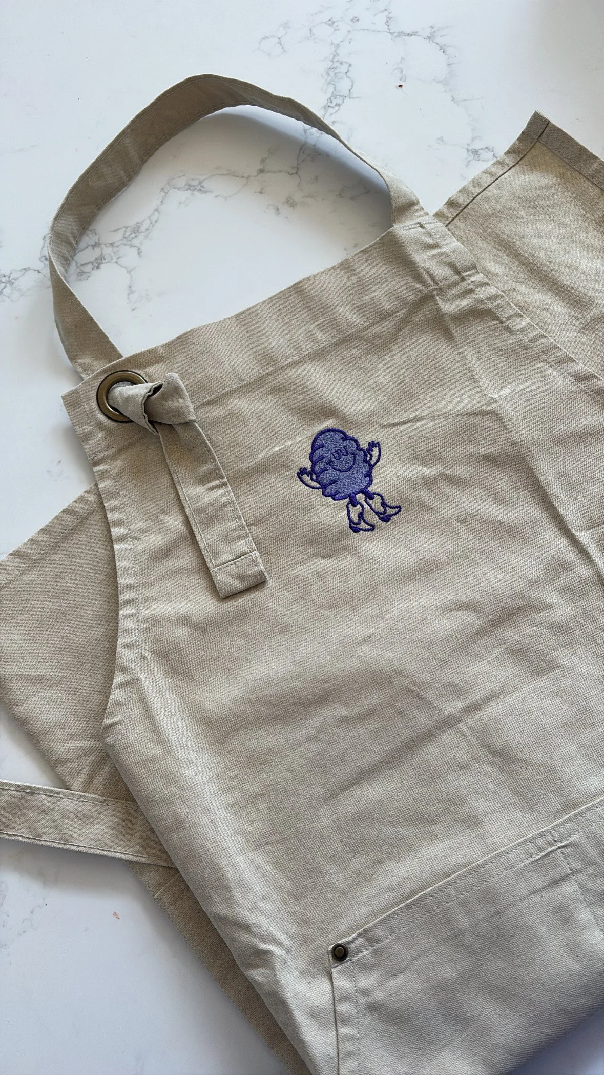 A linen Patatina apron with a purple Patatina.