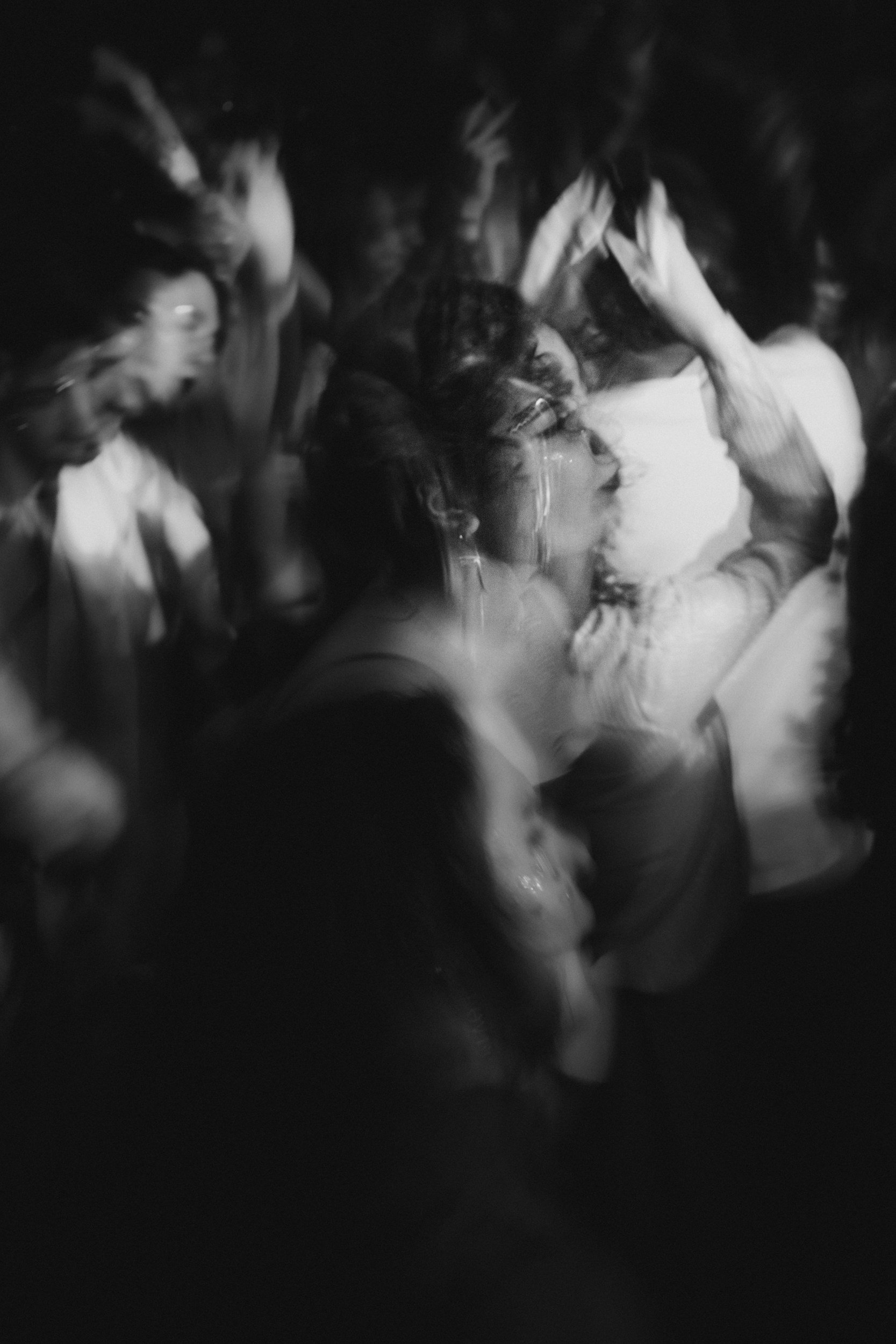 Black and white photo of a crowd of people standing close together,  at a concert or event, with motion blur indicating movement and a lively atmosphere.