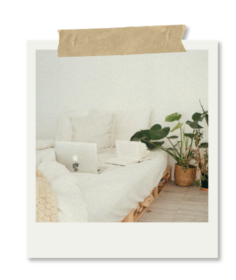 A living room with a white sofa, a laptop, and potted plants, taped to a tablet screen.