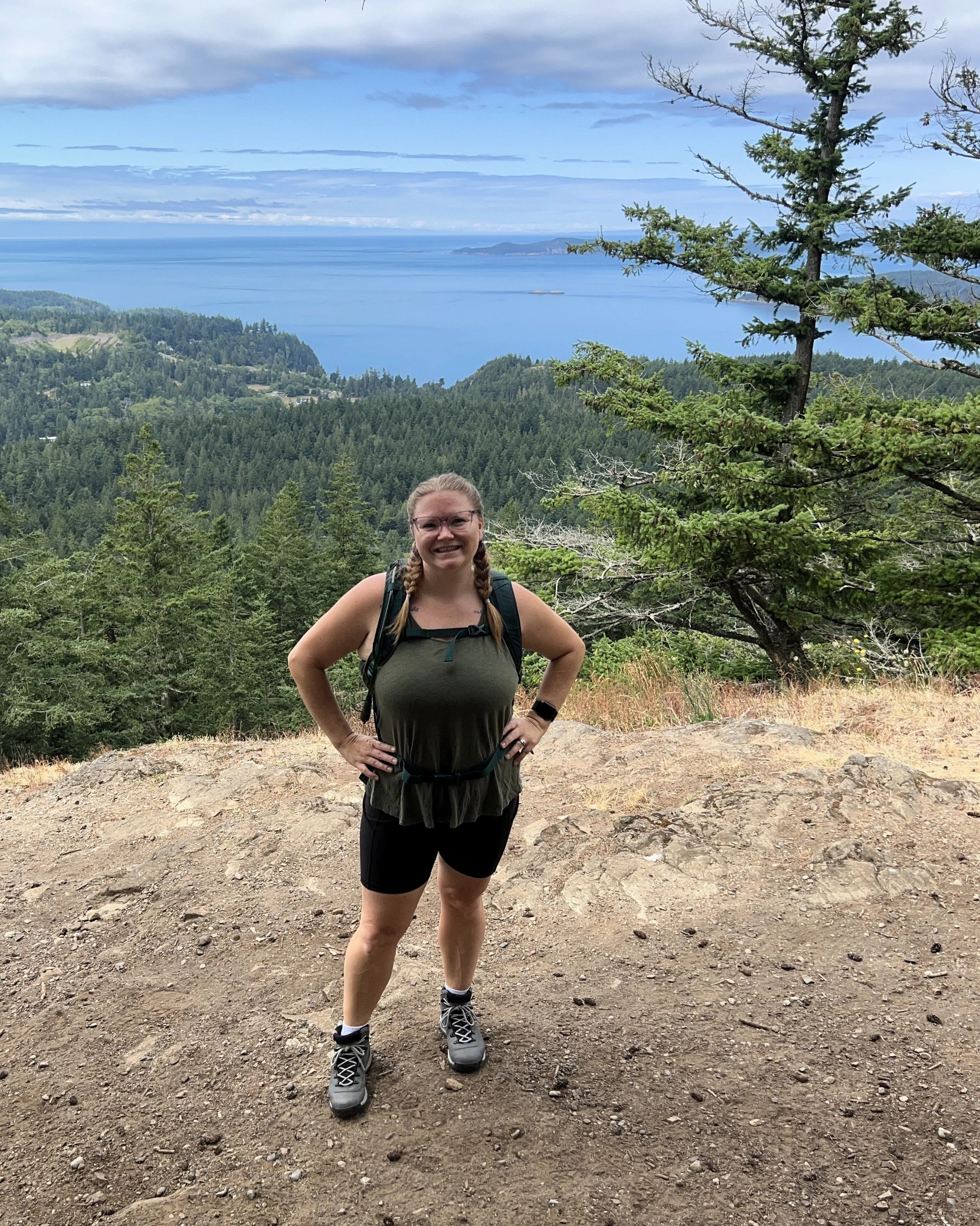 Woman standing on a mountain summit overlooking the ocean