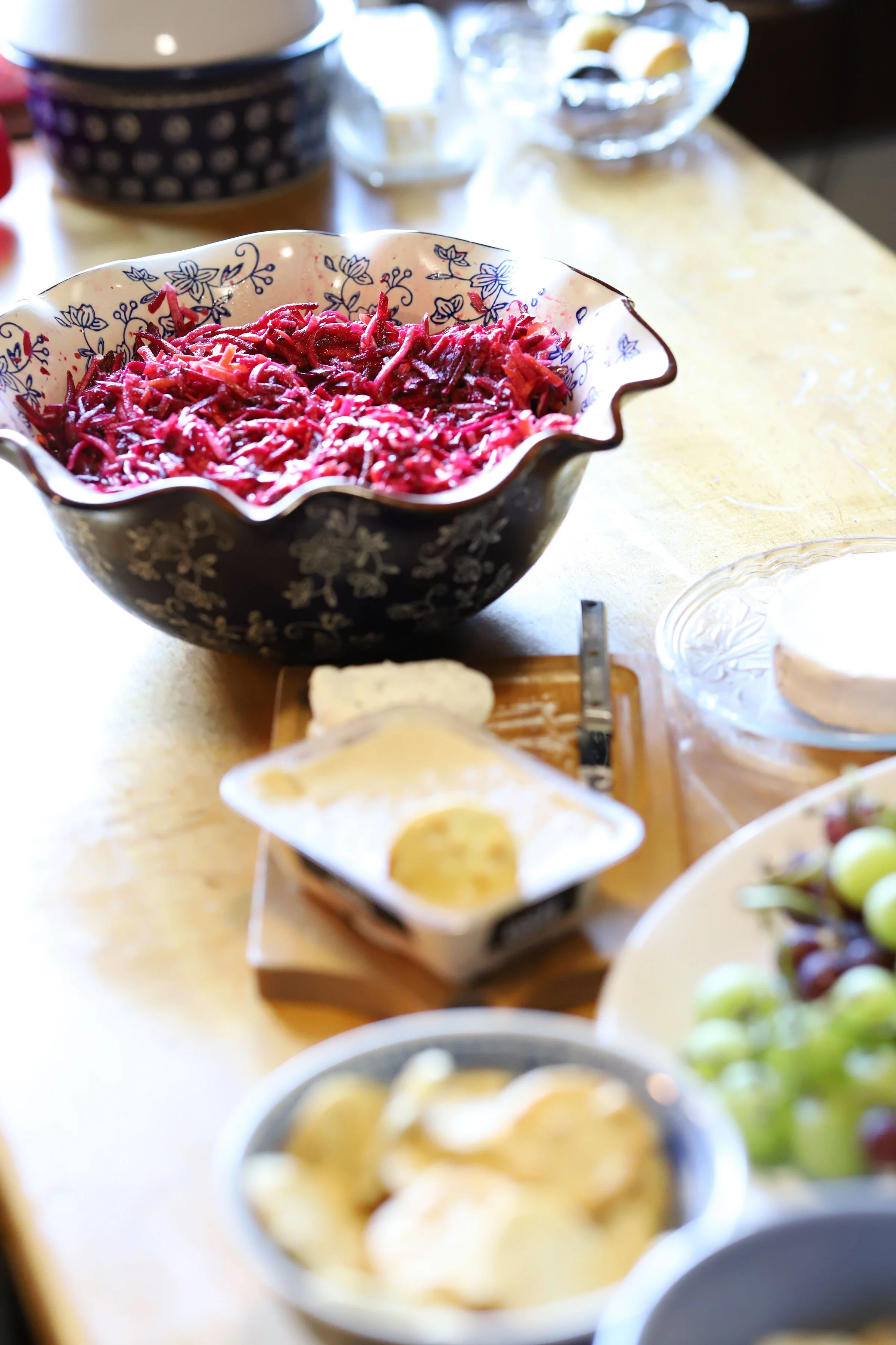 Bowl of shredded beets on a table with various dishes and glasses in the background.