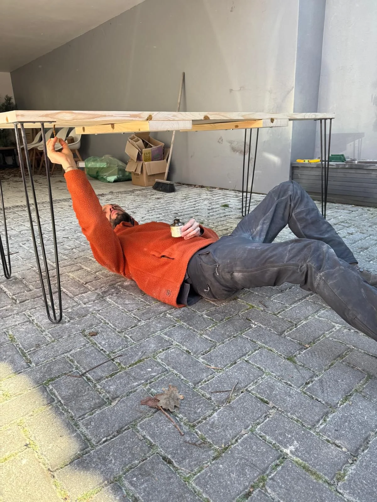 Carl lying on the ground, working on some carpentry work.