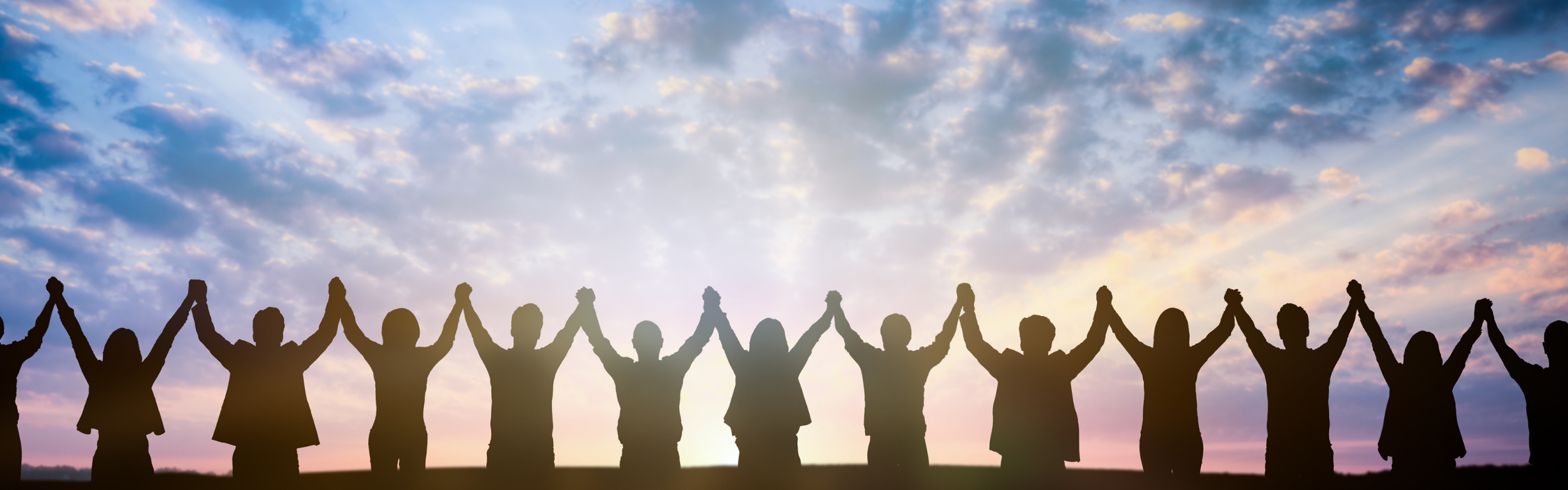 Silhouette of people holding hands in the air in front of a sun rise.