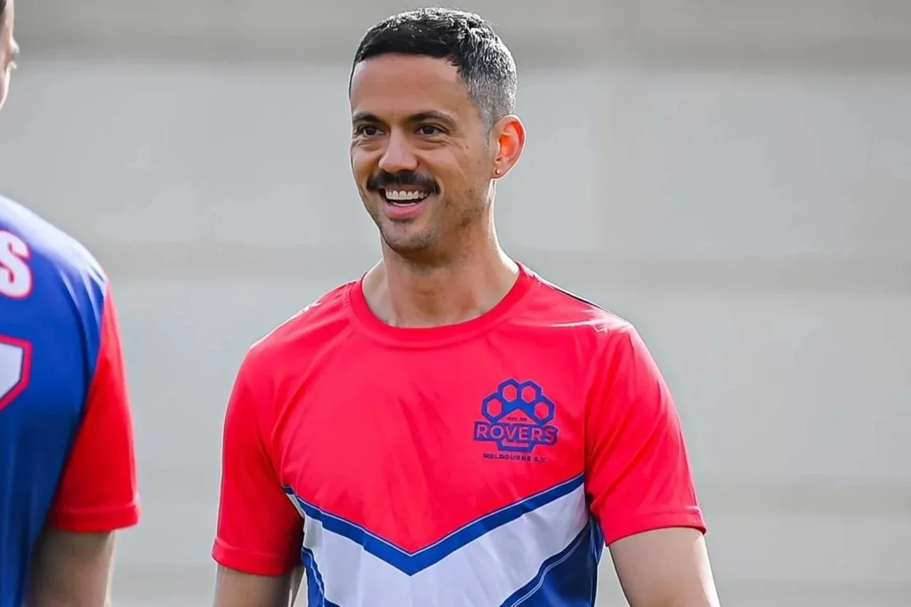 A smiling man in a red and blue sports jersey with a logo that reads "ROVERS", participating in a sports event.