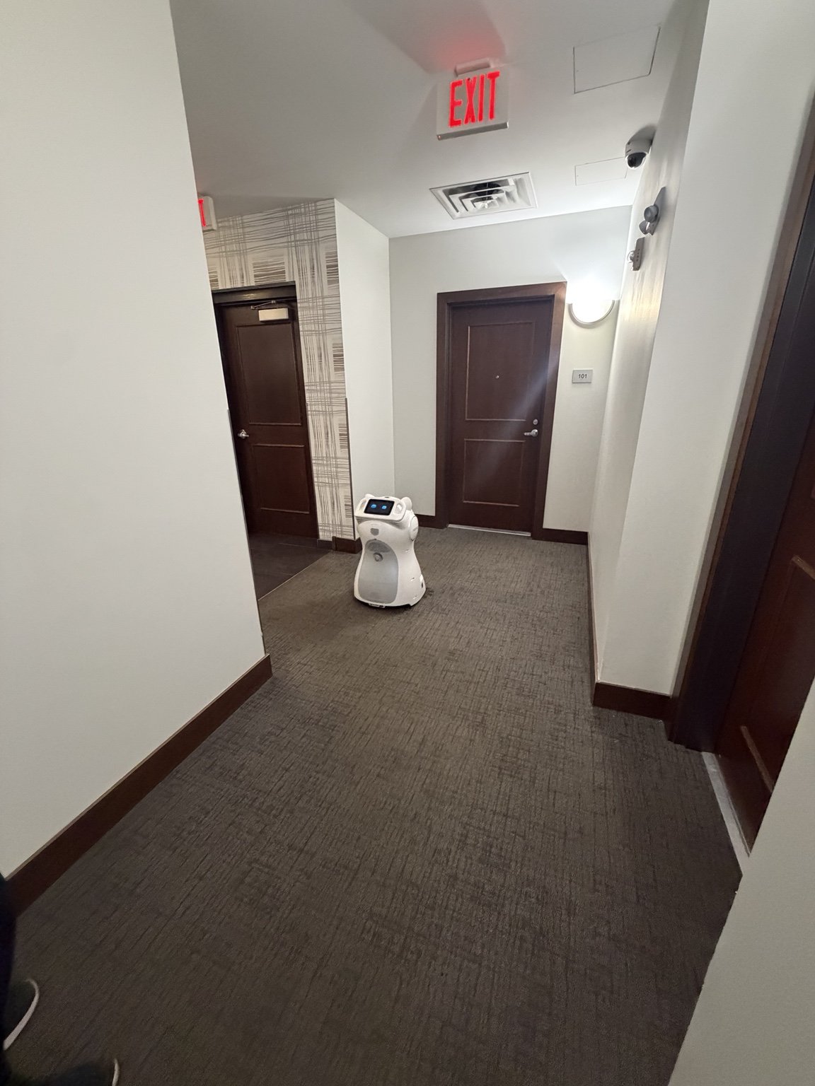 KEENON C30 cleaning robot on a carpeted hallway route at Boutique 28 Apartments.