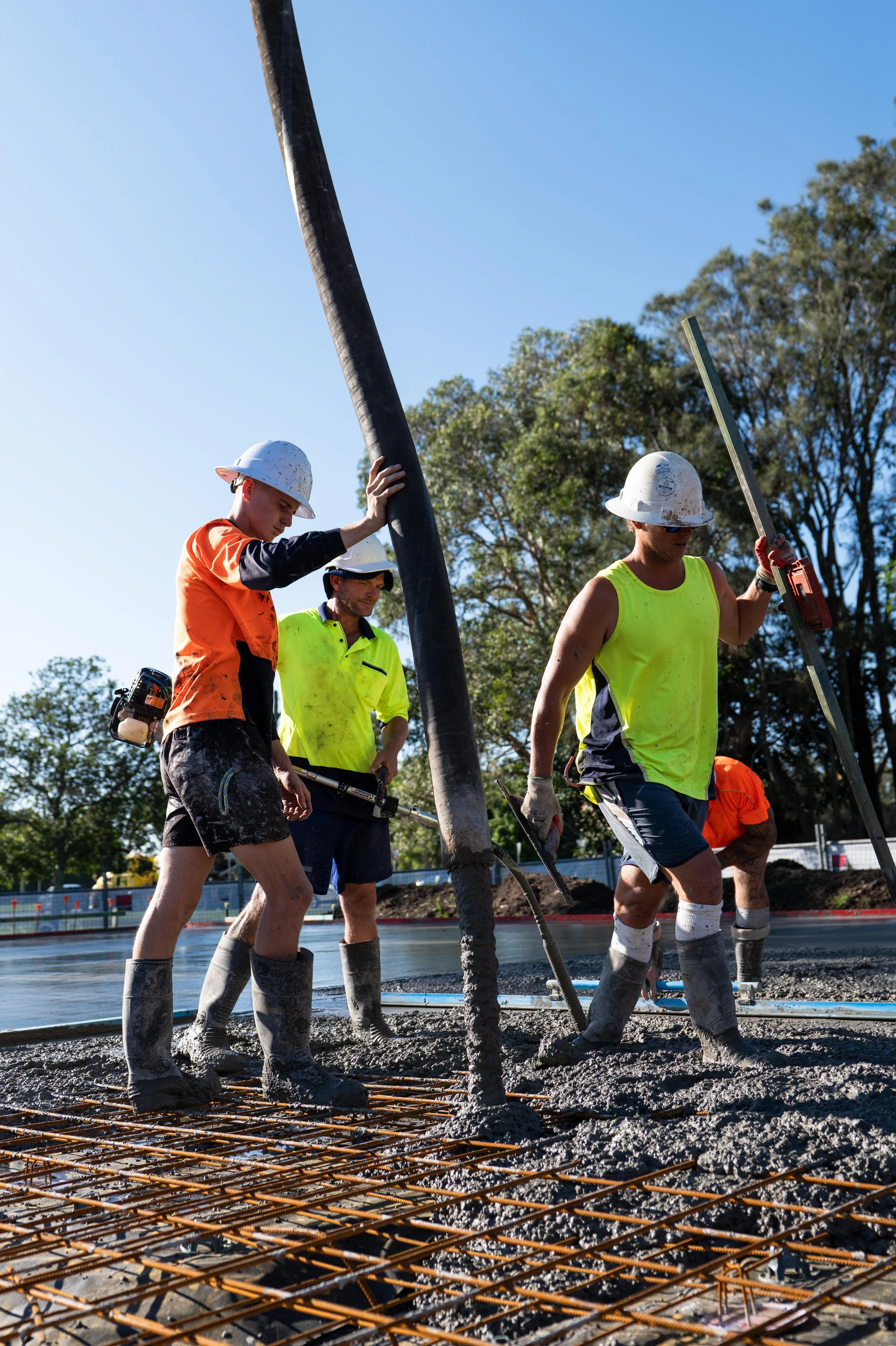 Construction workers pouring concrete on a construction site during daytime.