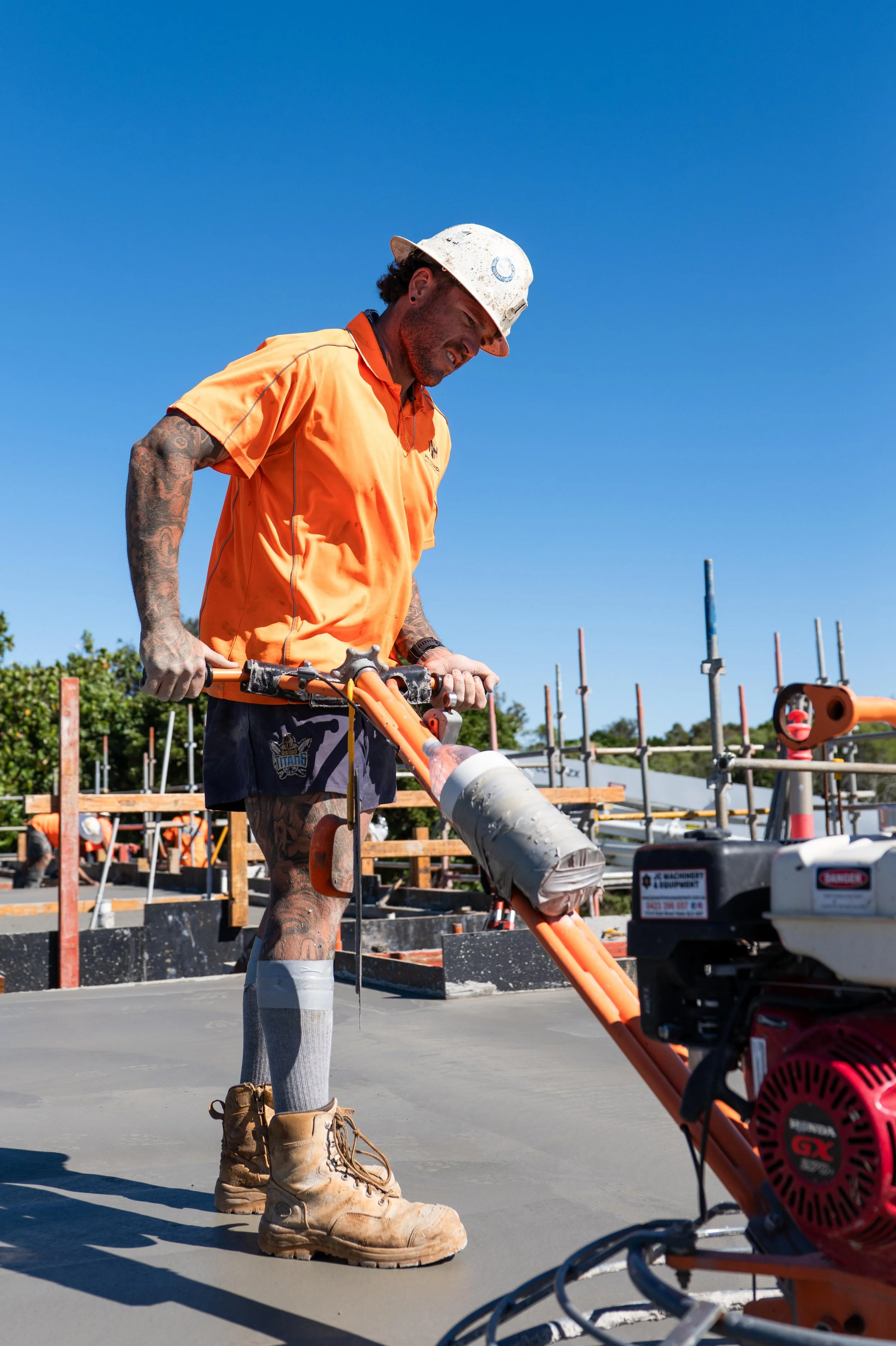 Construction worker using a power tool on a concrete surface.