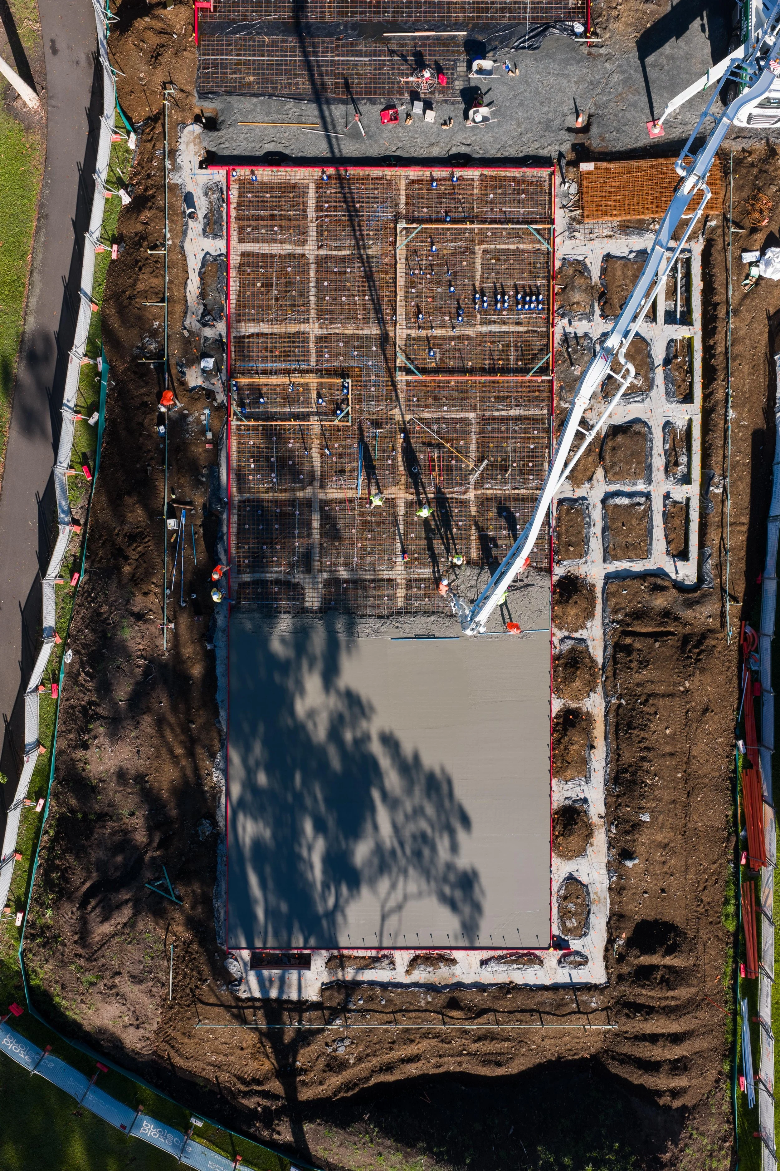 Aerial view of a building construction site showing foundation work and concrete pouring in progress.