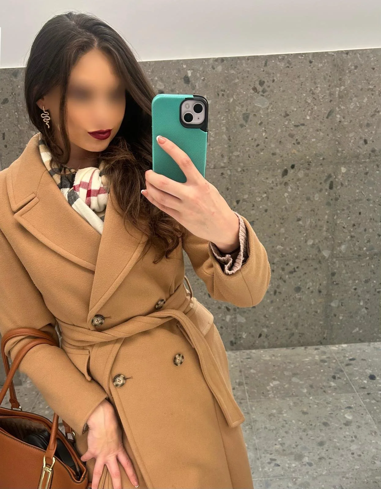 A woman in red lipstick and burberry scarf with a camel-coloured coat on