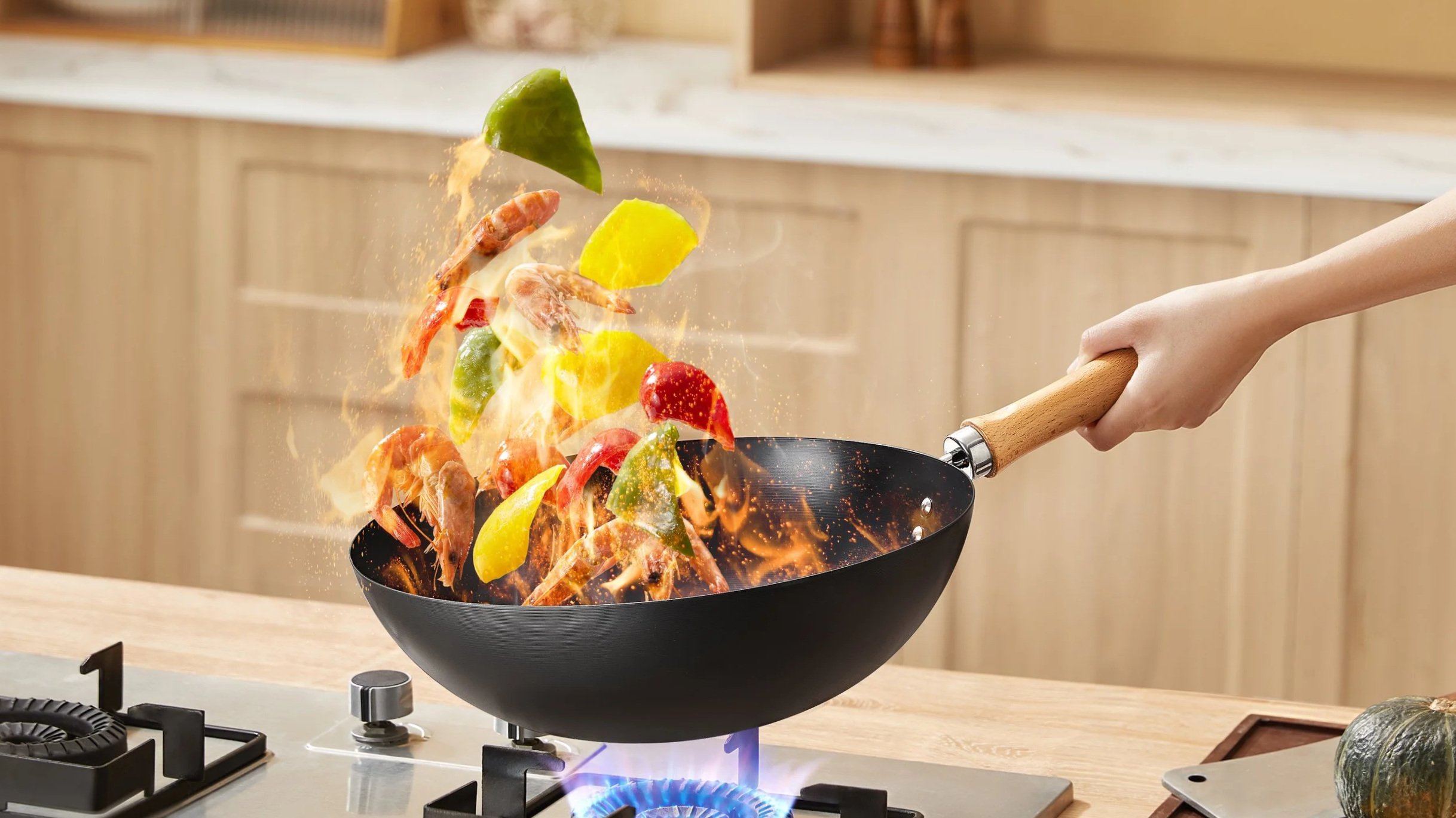 Vegetables being tossed in a frying pan over a gas stove with a blue flame, in a kitchen.