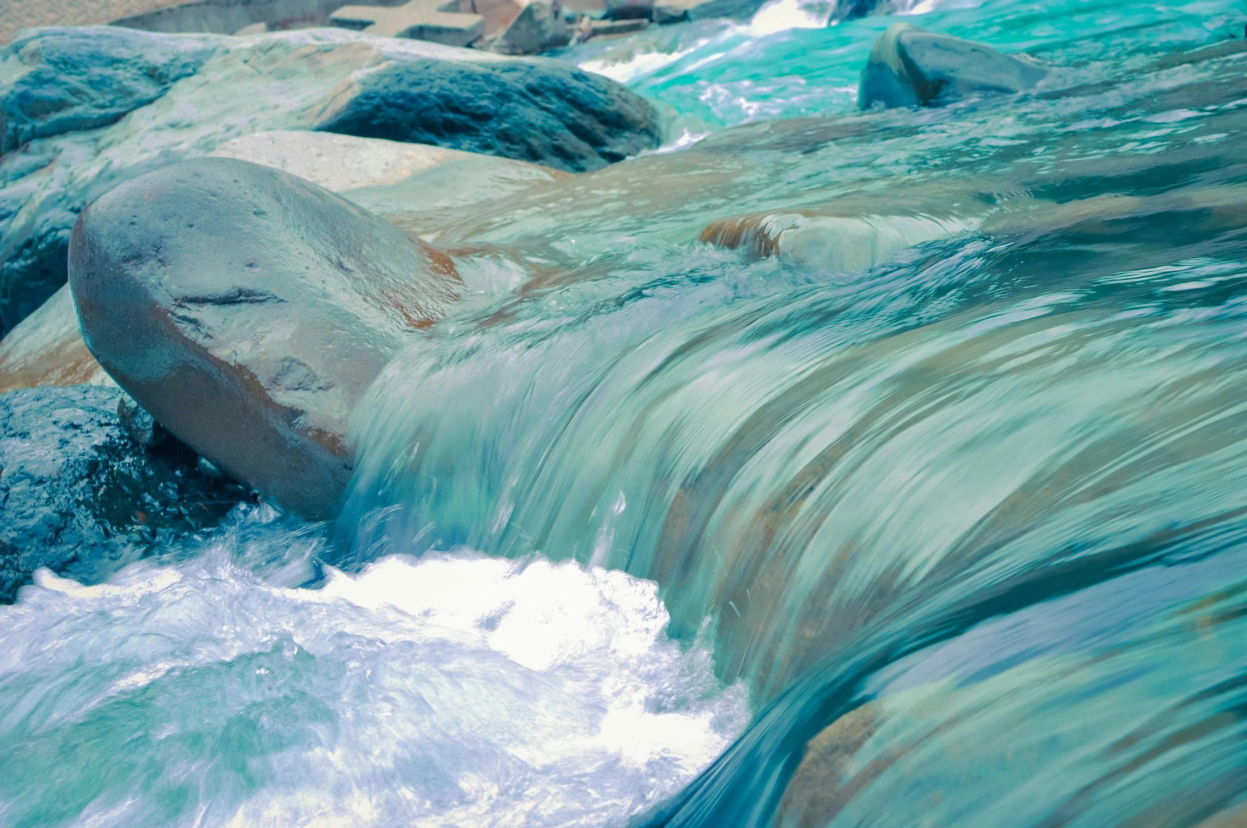 Flowing turquoise water over rocks in a river