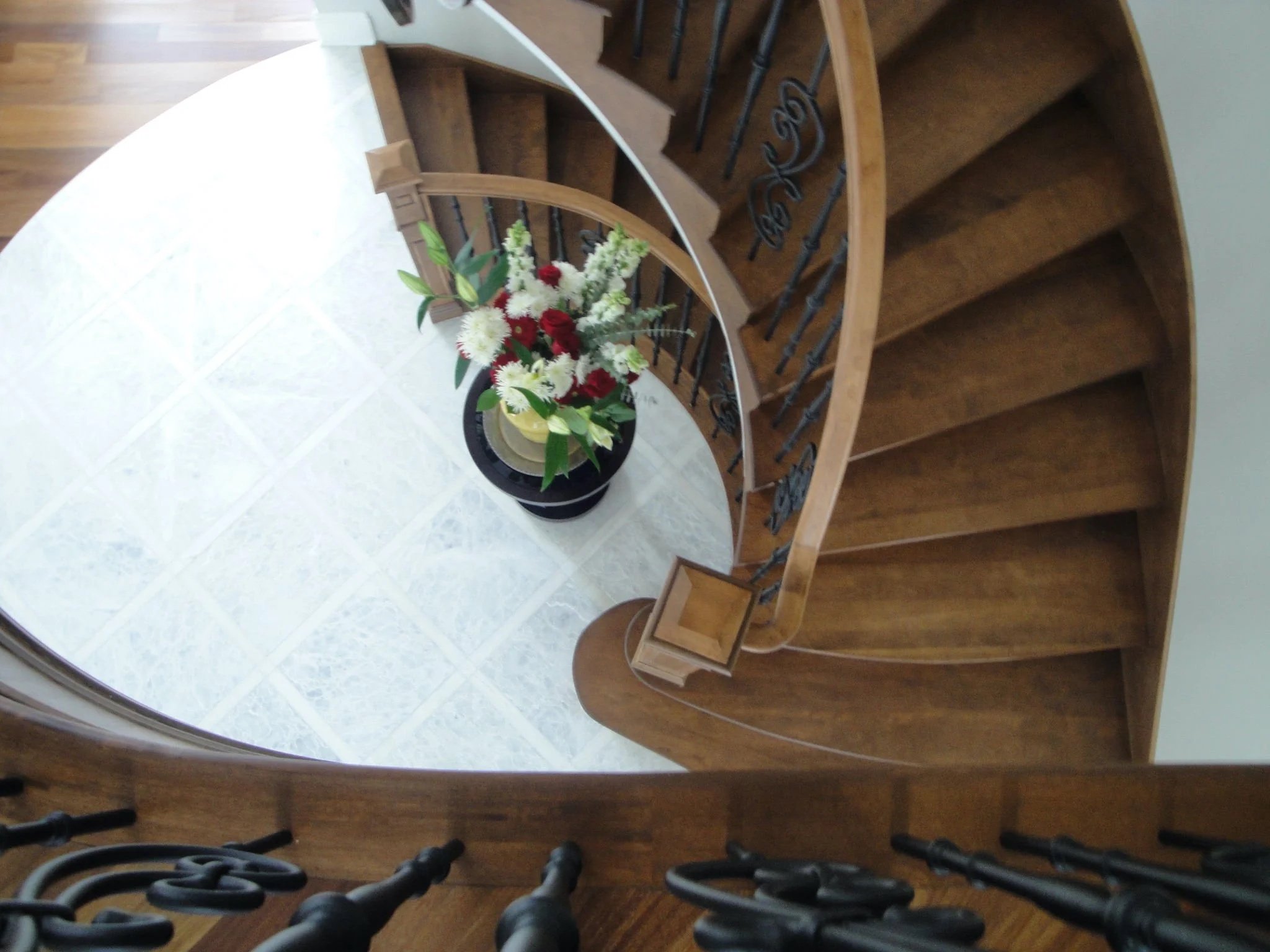White marble installation in a Beaconsfield residence, West Island Montreal, creating a striking contrast with the adjacent wood staircase, blending natural materials with a clean, modern aesthetic