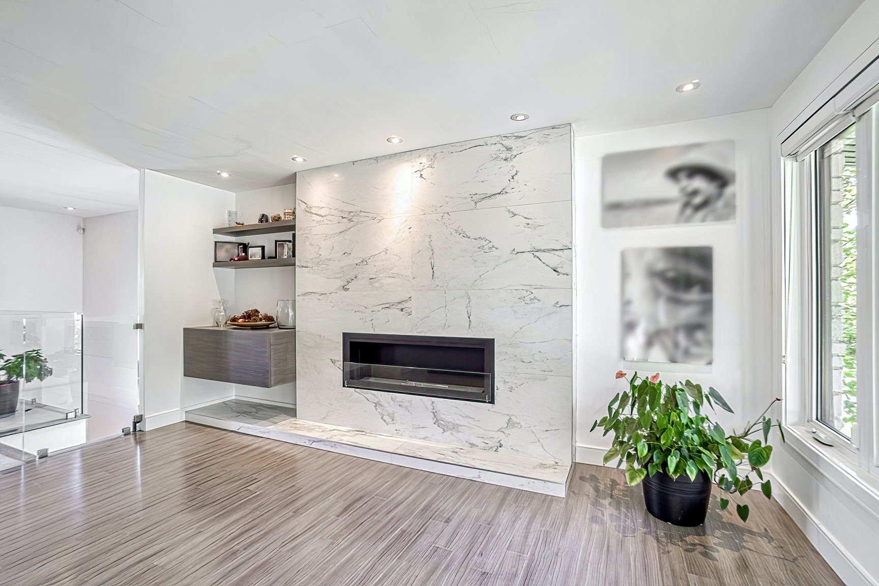 Complete transformation of a Pierrefonds bungalow, West Island Montreal, creating an open-concept living space with a striking modern fireplace in the center, wrapped in extra-large white tiles for a sleek and impressive look
