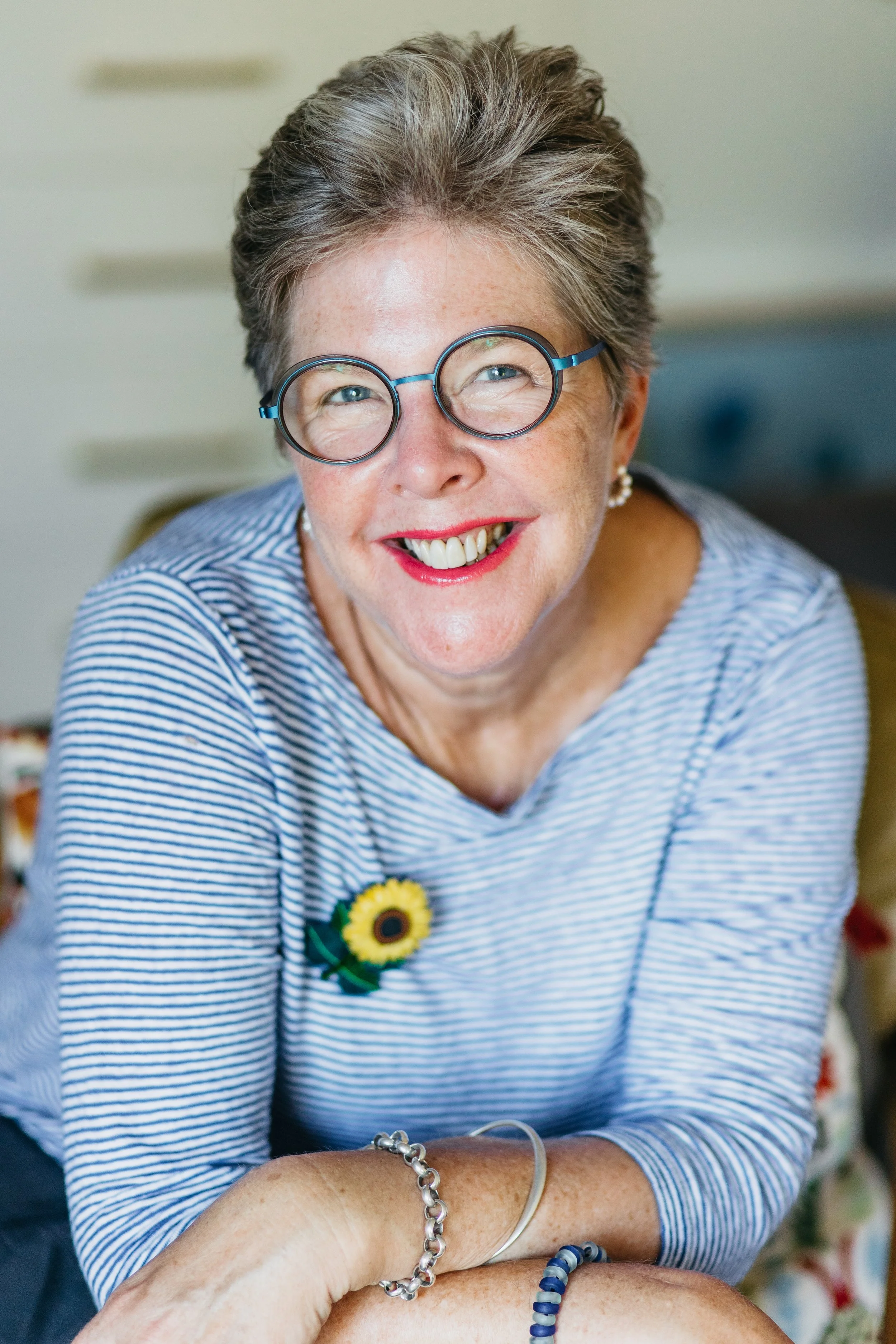 Woman in striped shirt and glasses looks at camera