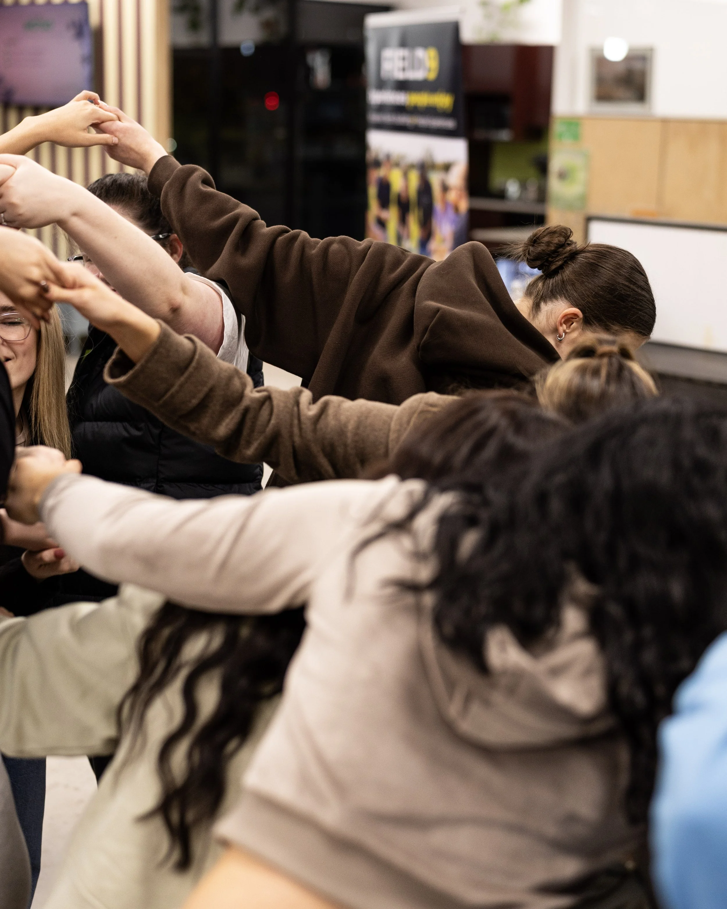 People forming a human chain with hands joined together,  engaging in a Field9 team building experience in Adelaide.