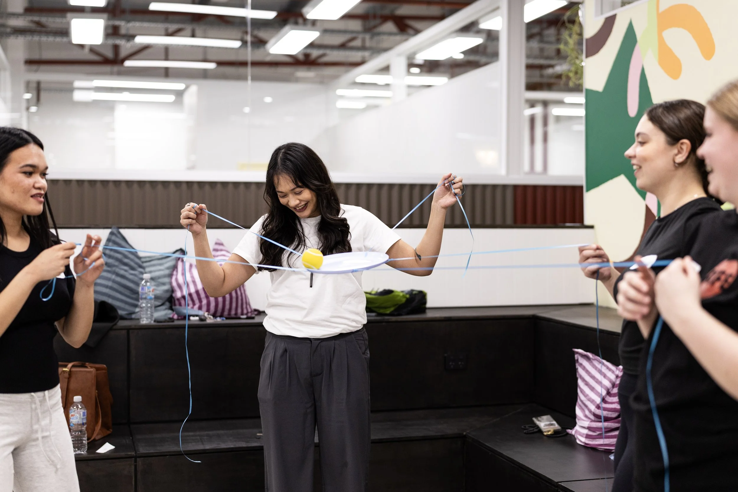 Group of people playing a game with string and a small ball in an engaging Field9 team building experience in Adelaide.