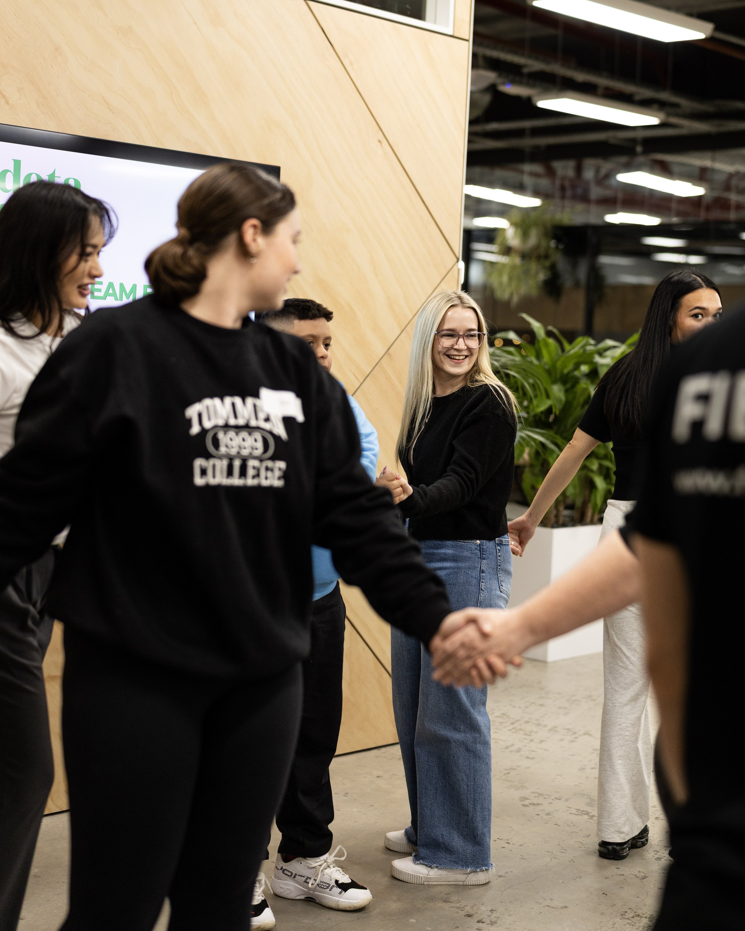 People shaking hands in a handshake line at a Field9 team building experience in Adelaide, smiling and engaging with one another.