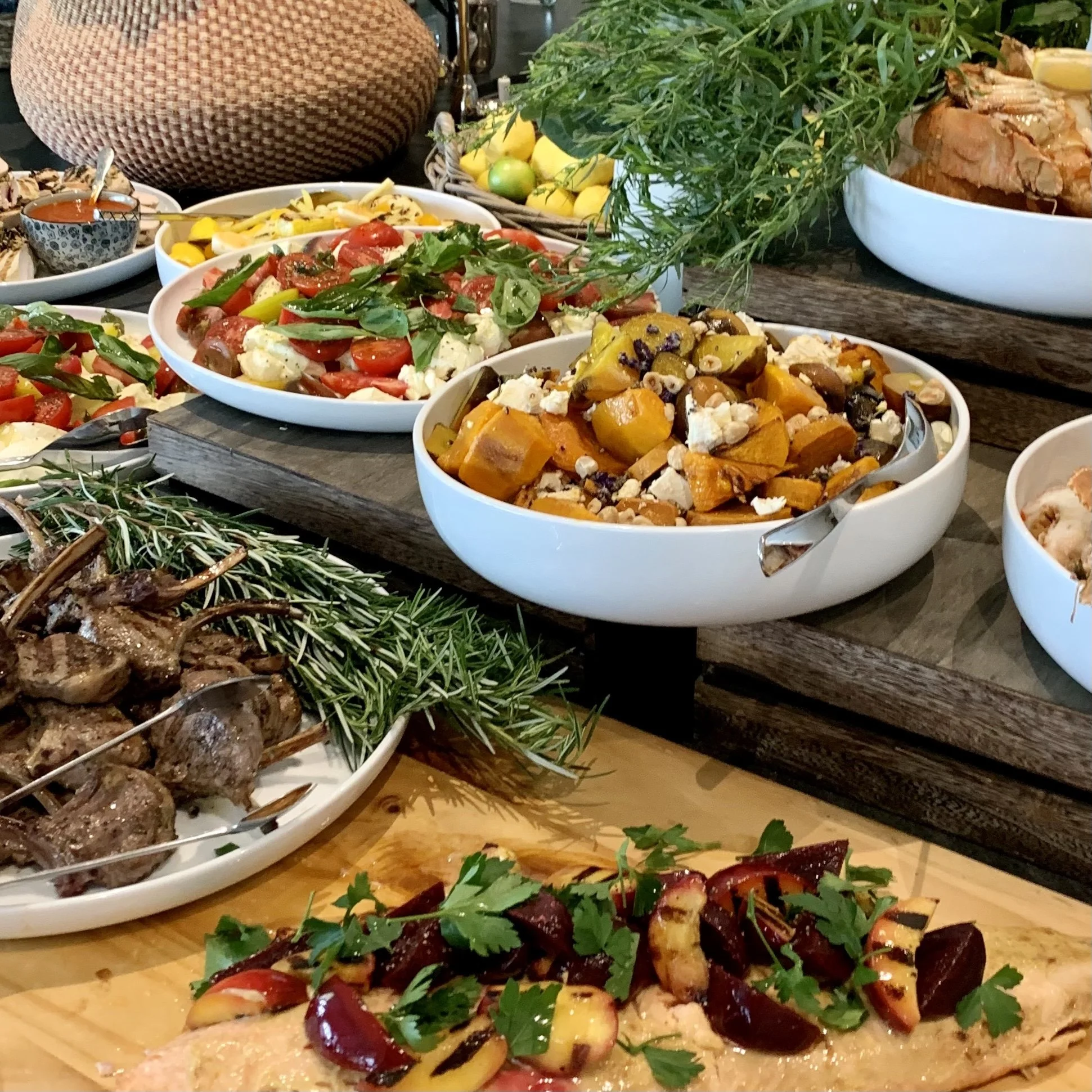 Assorted dishes including roasted vegetables, fresh salads, grilled meat, and garnishes on a buffet table.