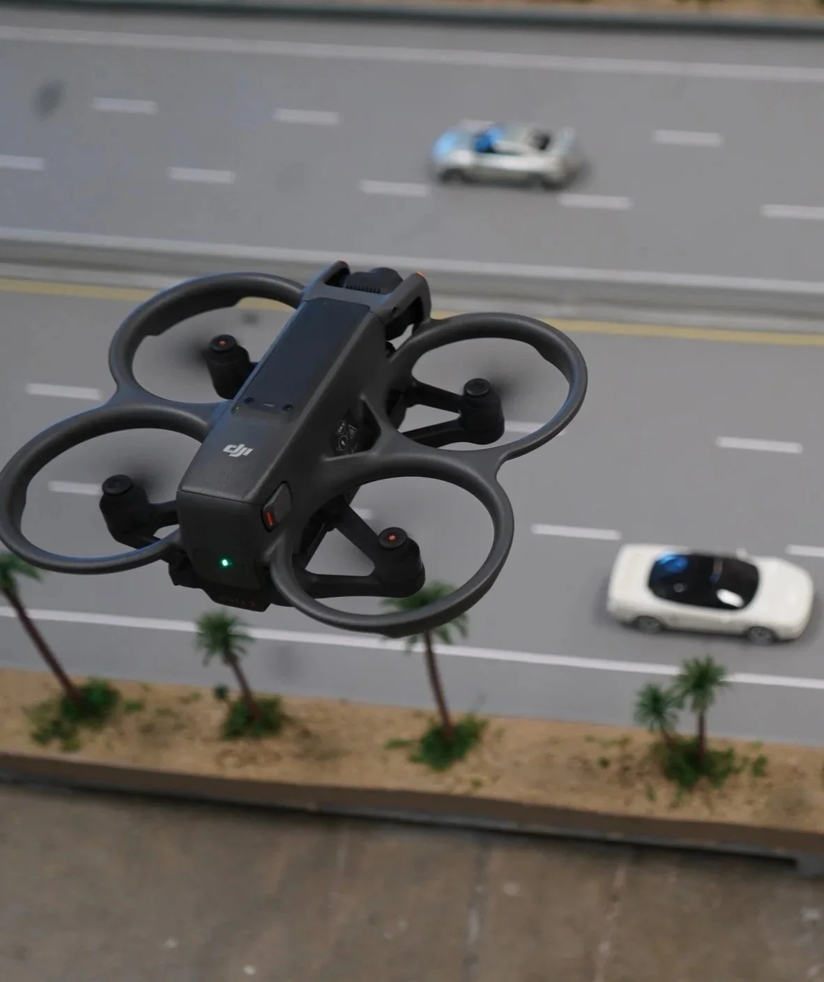 A drone is flying above a freeway while filming and tracking the cars below on a large freeway model at California Drone Academy.